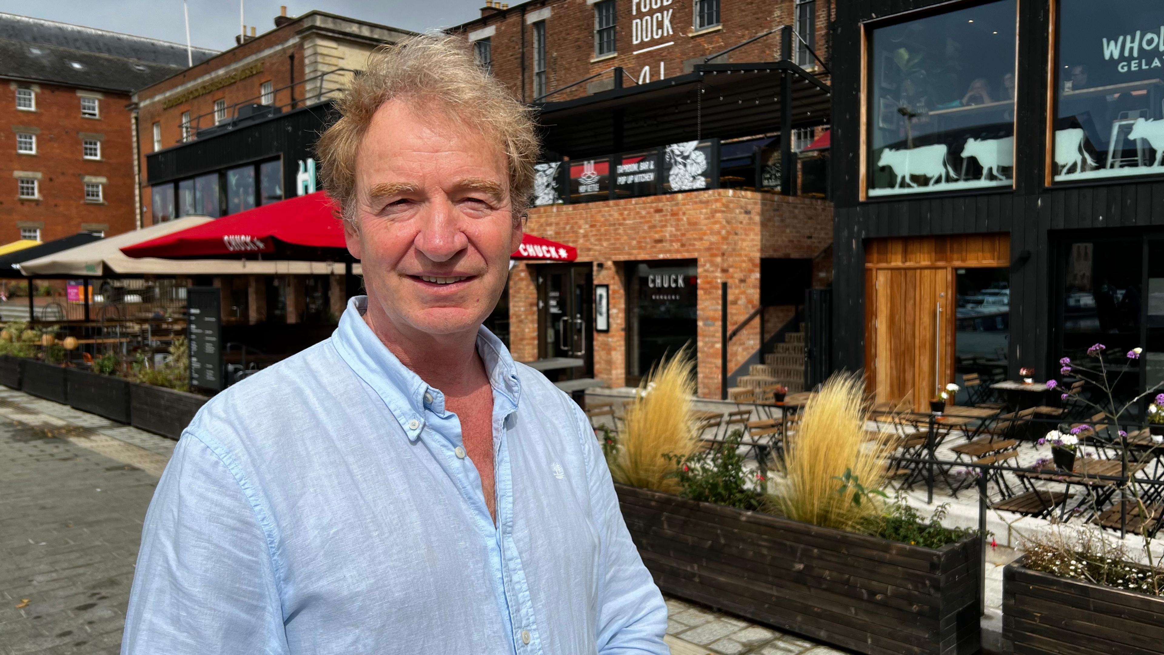 Property developer Ken Elliott stands in front of his Food Dock development in a blue shirt.