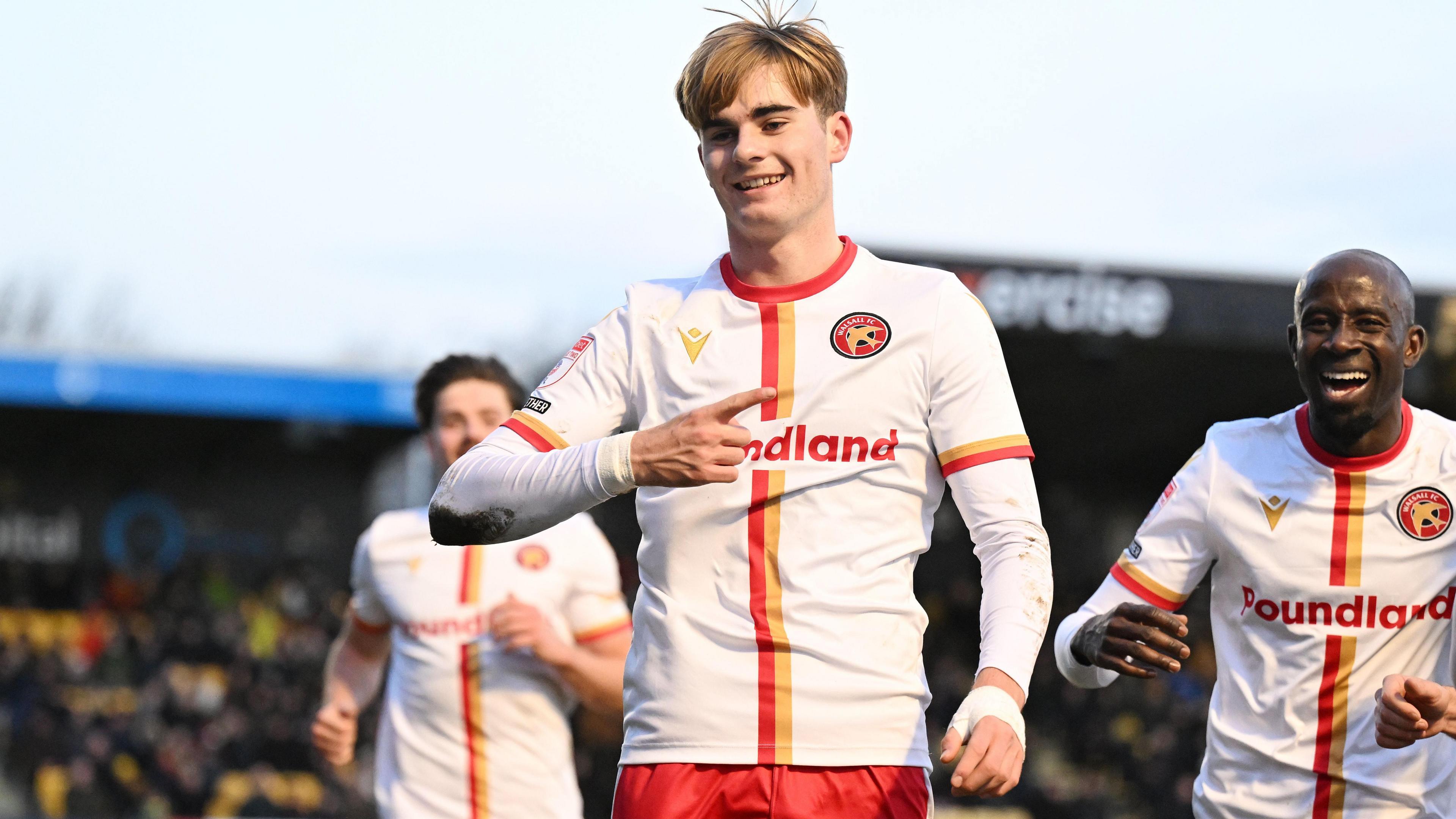 Nathan Lowe celebrates scoring for Walsall with his team-mates rushing to congratulate him.