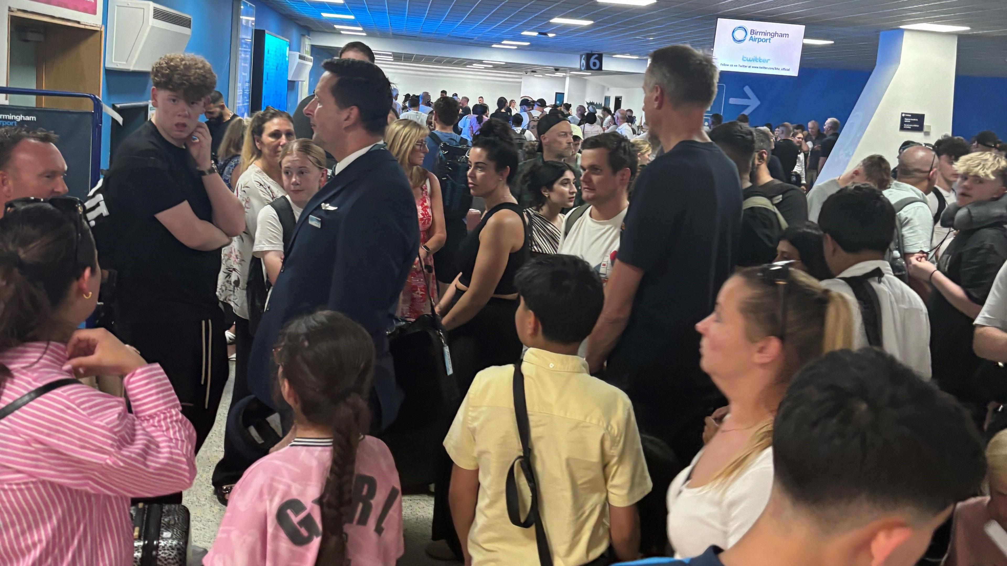 A large group of passengers at Birmingham Airport baggage reclaim