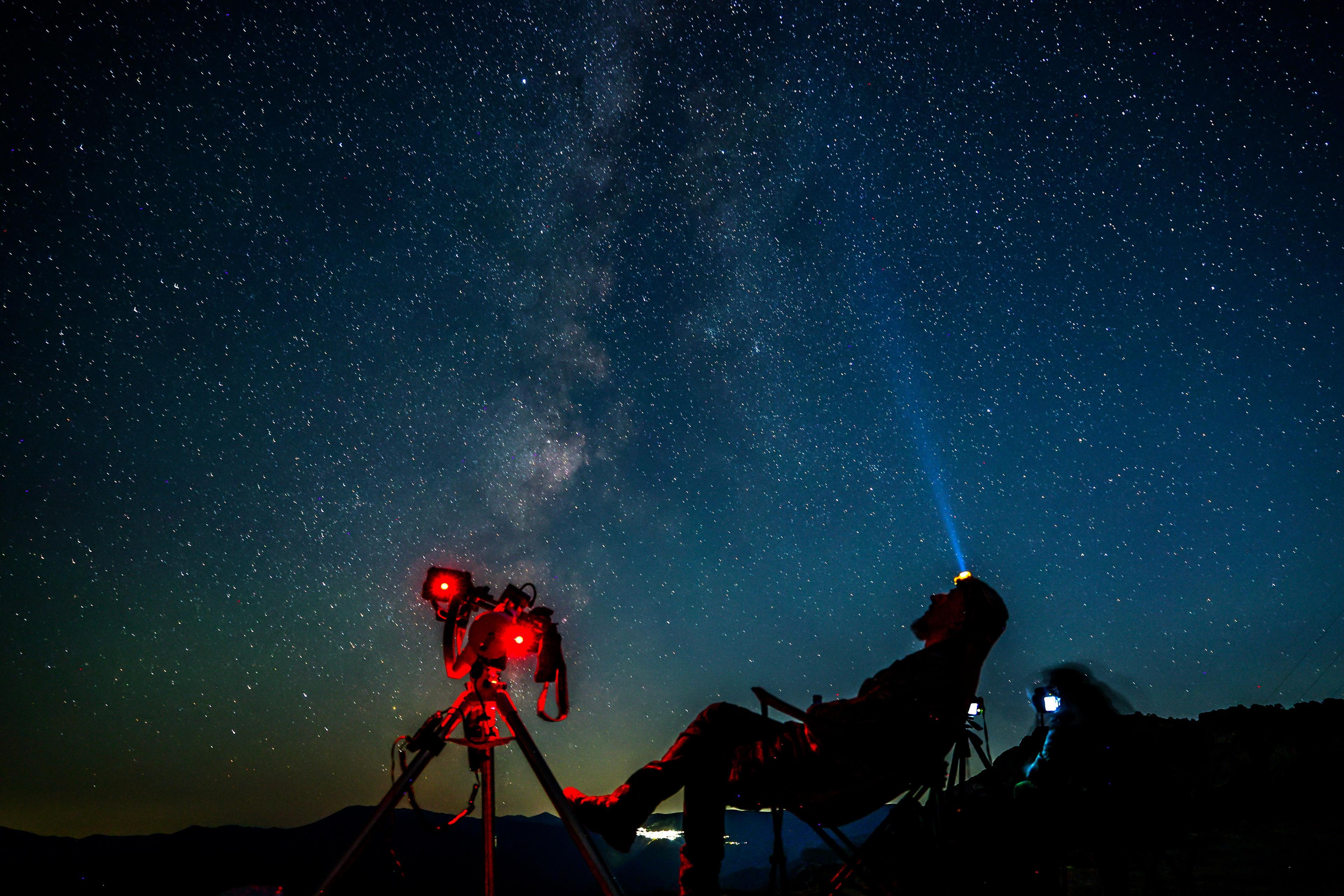 A man sits by his cameras and watches the sky 