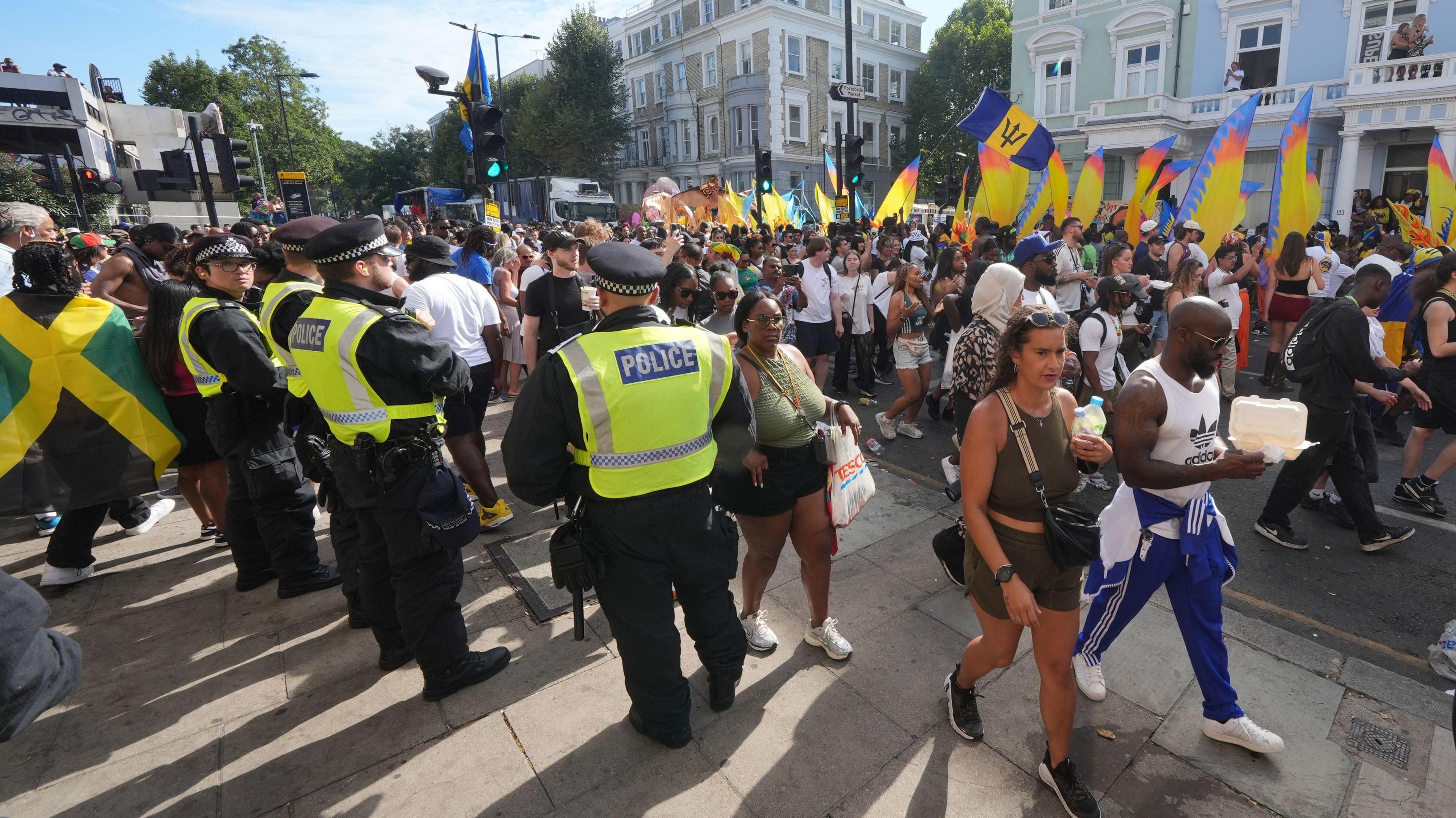 A row of police officers standing on the route of the carnival