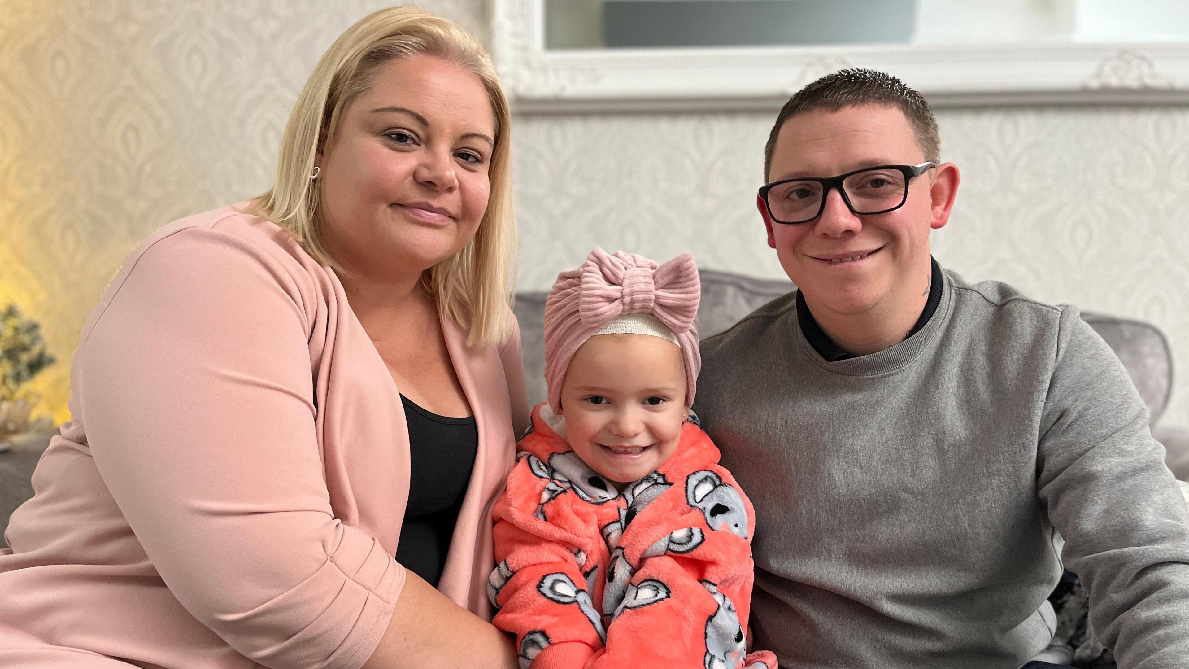 Girl sits between her parents