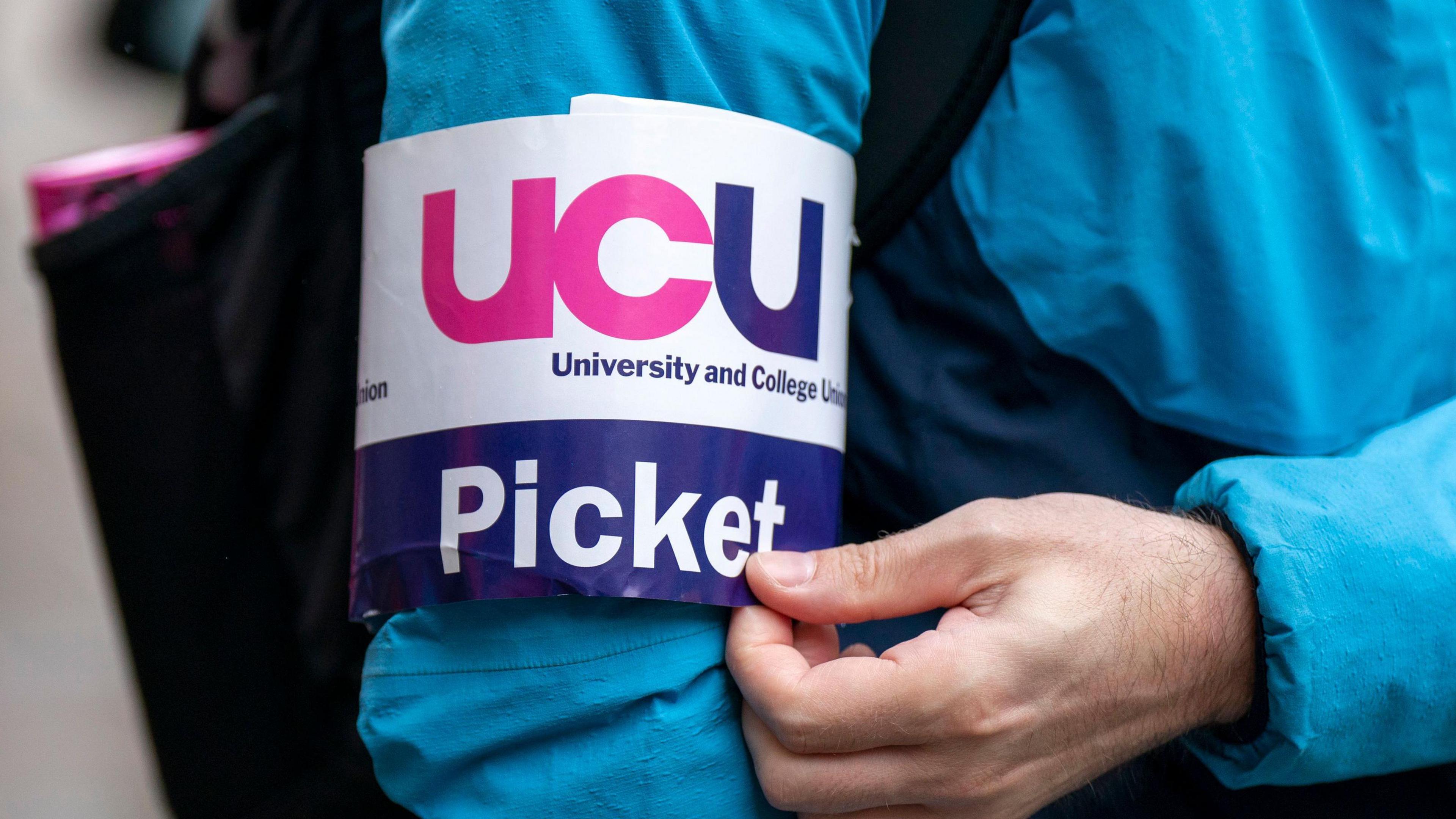 A UCU picket armband on a person wearing a blue coat at a strike
