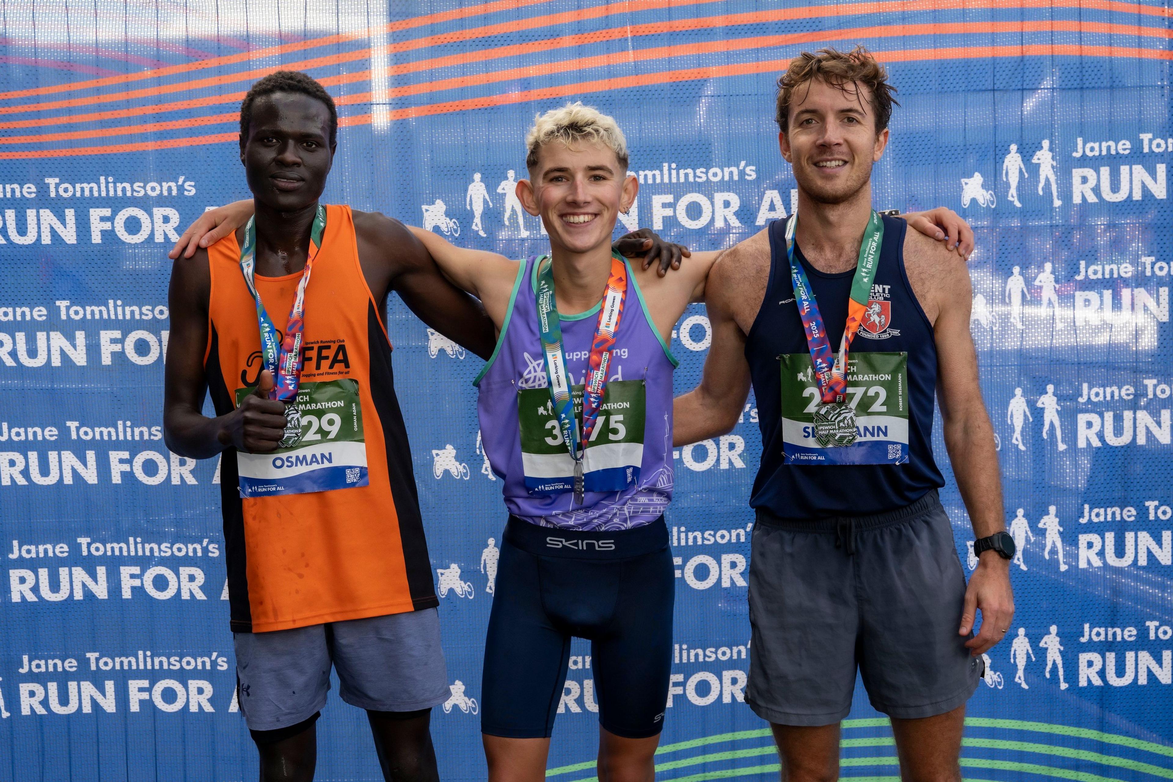 Three men wearing medals at the finish line of the half marathon
