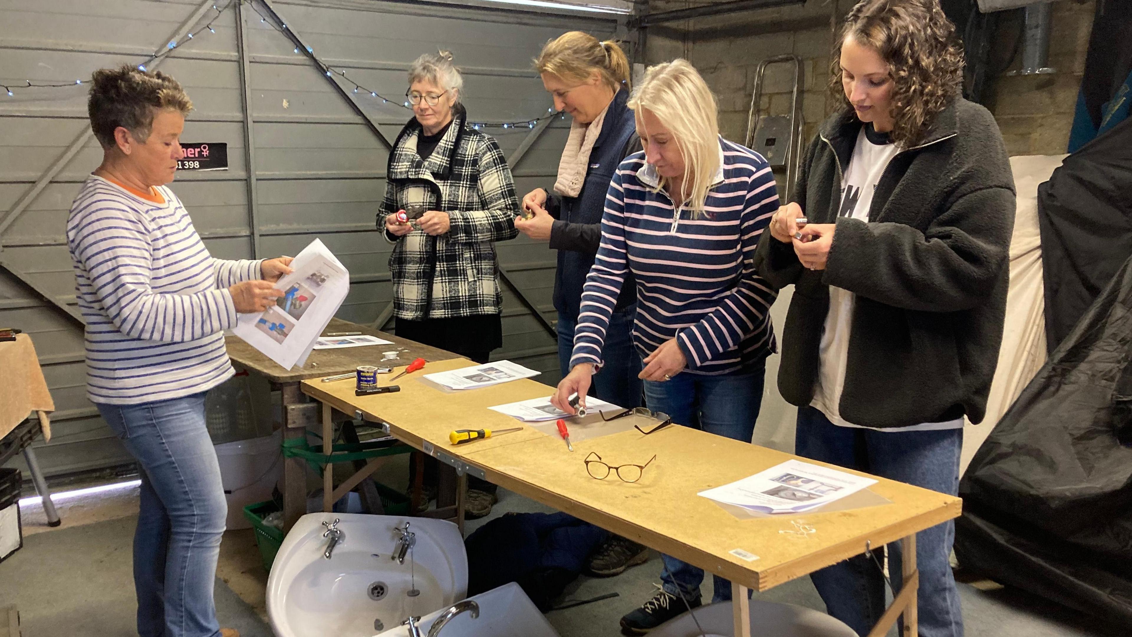 Four women being taught basic plumbing skills