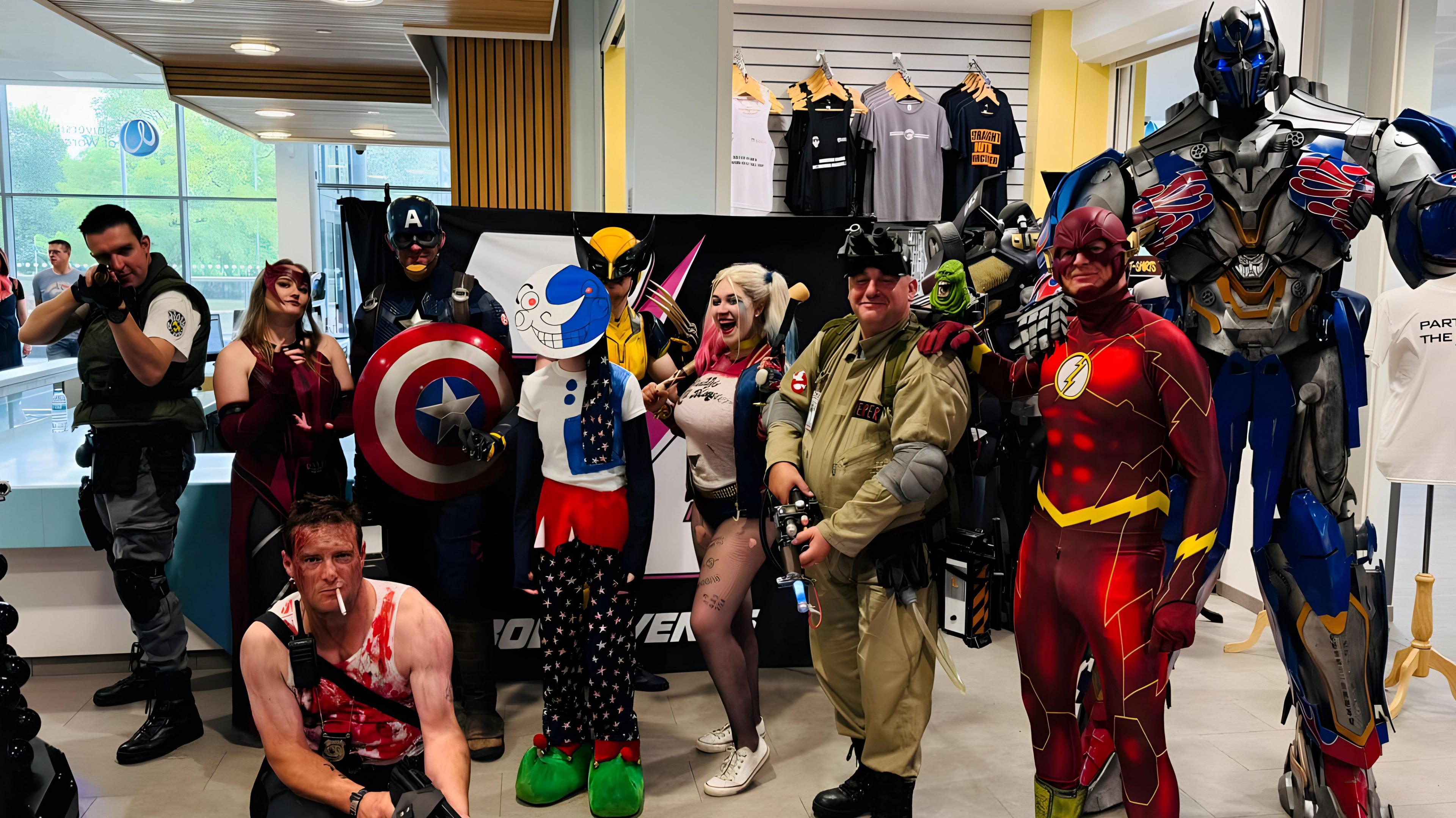 A group of cosplayers including Wolverine, Harley Quinn and The Flash are stood on a convention floor.