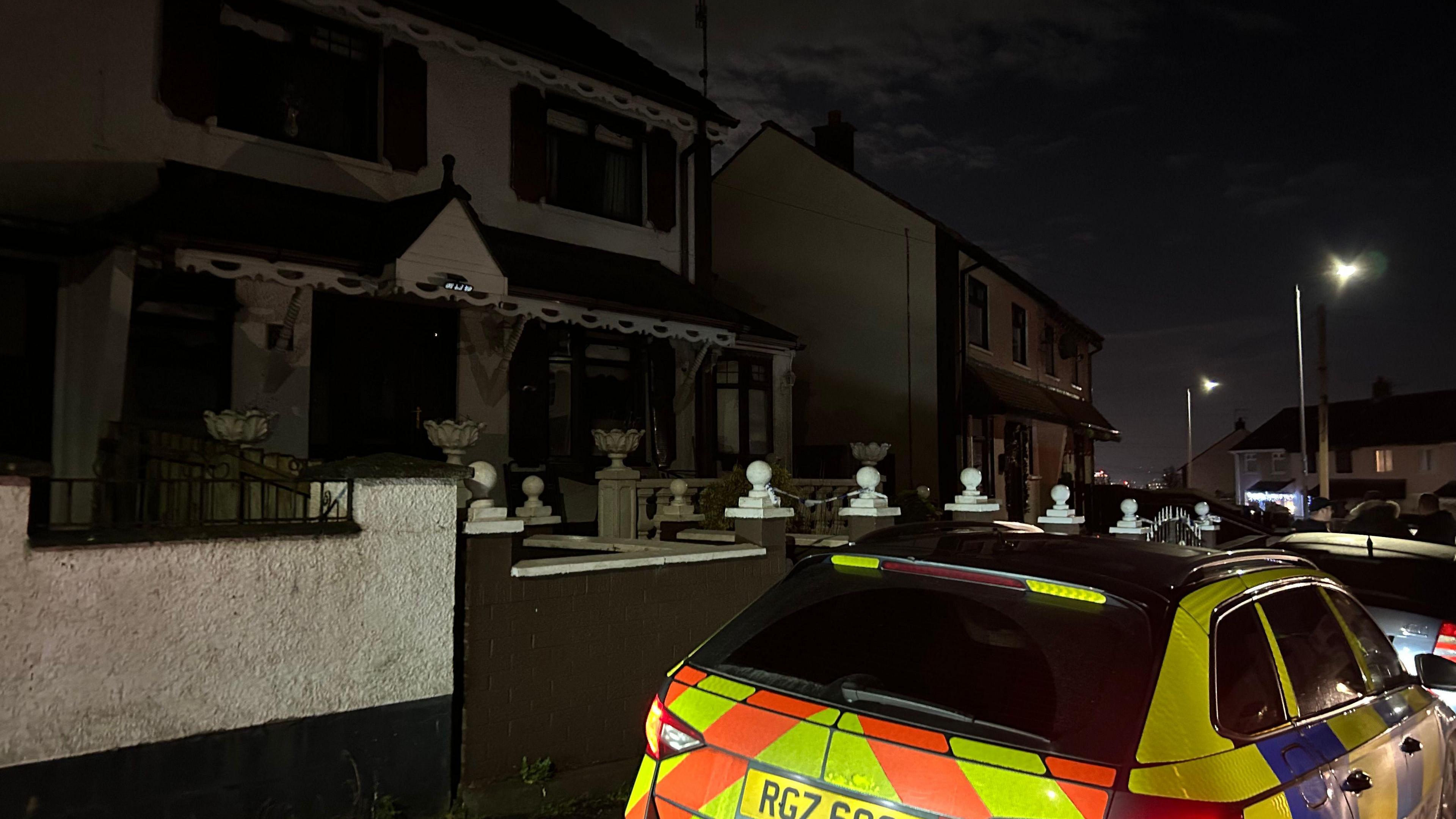 A house viewed from the road with a police car parked outside