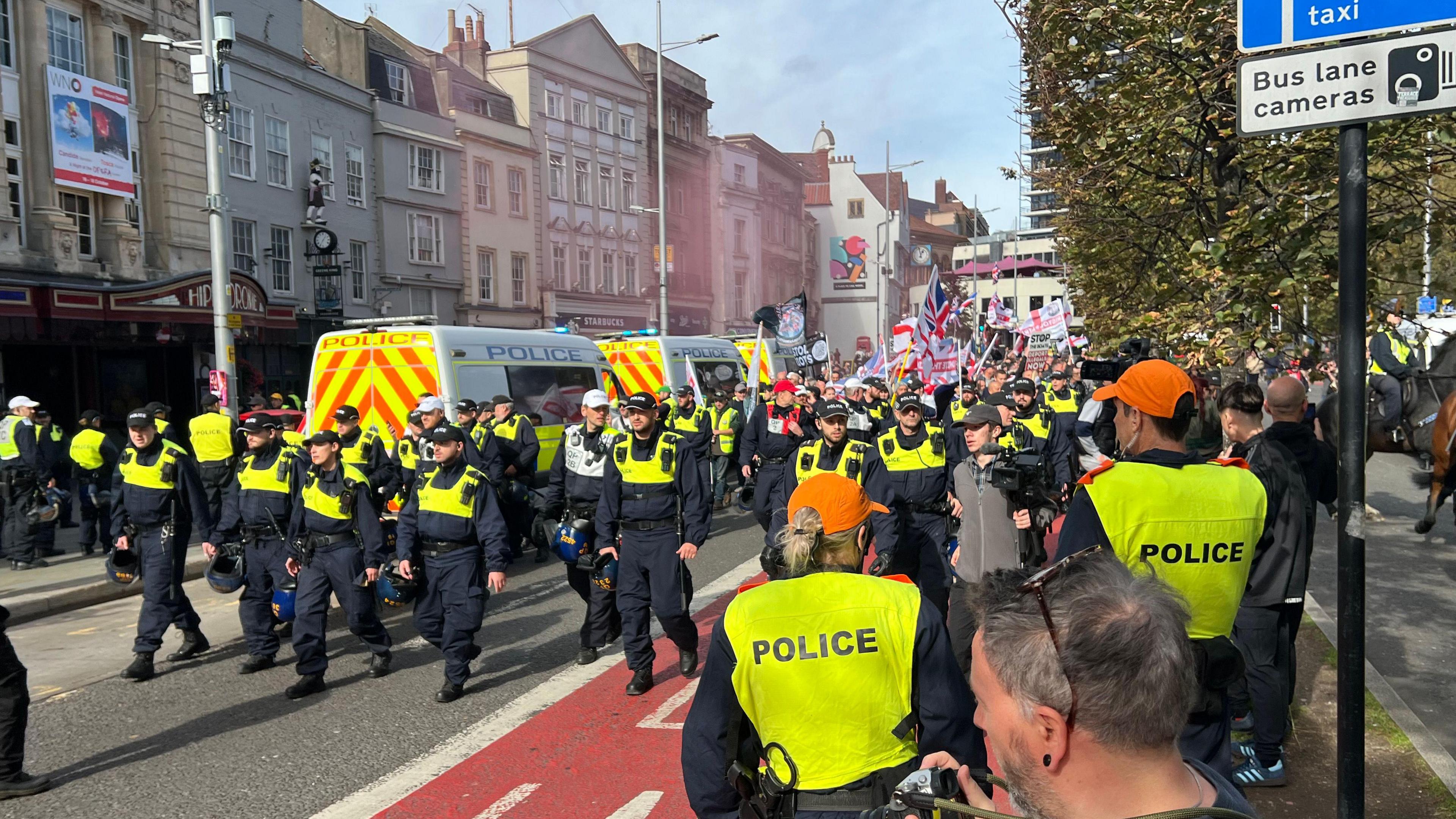 Large police presence in front of marching protesters waving Union flags and English flags