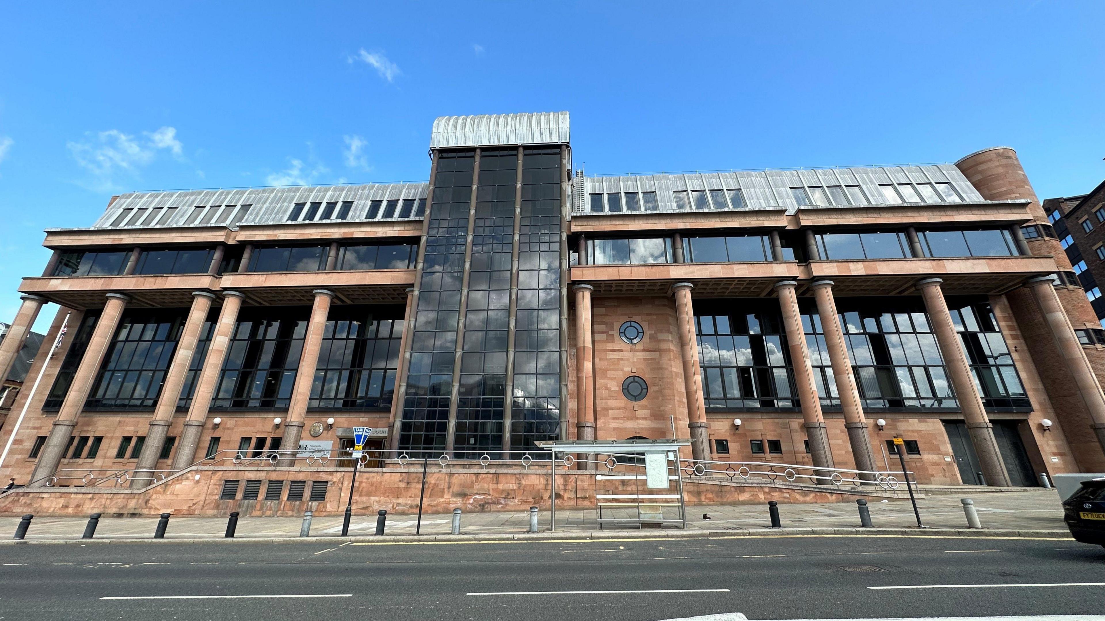 A court building. It is several storeys tall and has red walls and large black windows