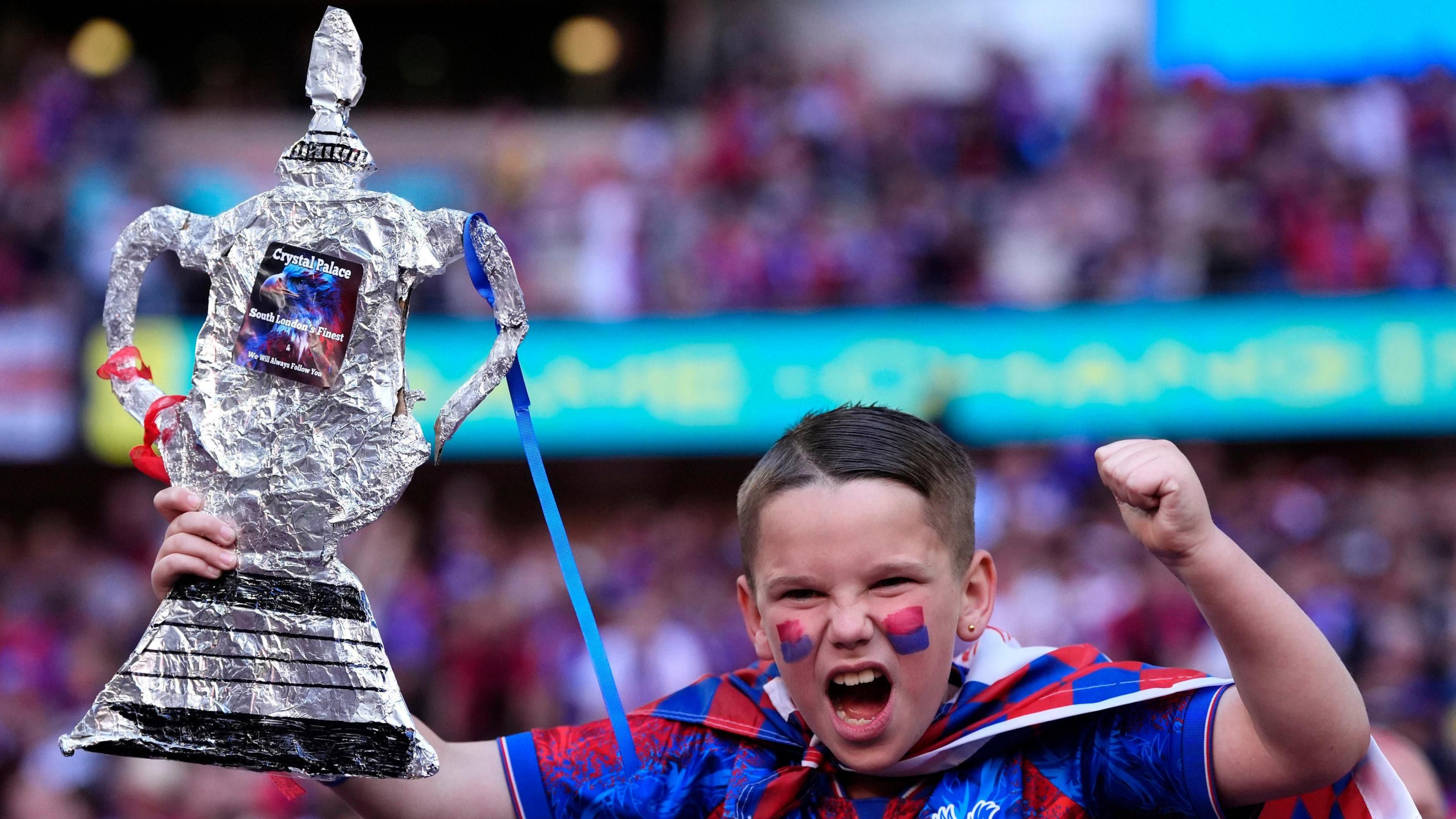 A young fan with his homemade FA Cup in the crowd