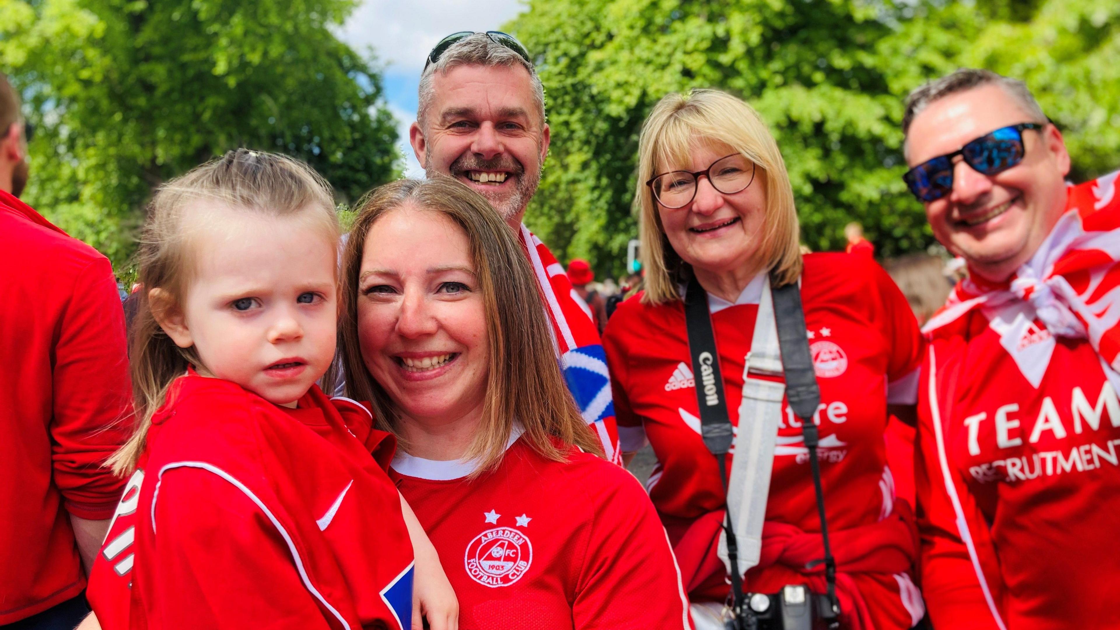Young girl dressed in red with other family members also in red, all smiling.