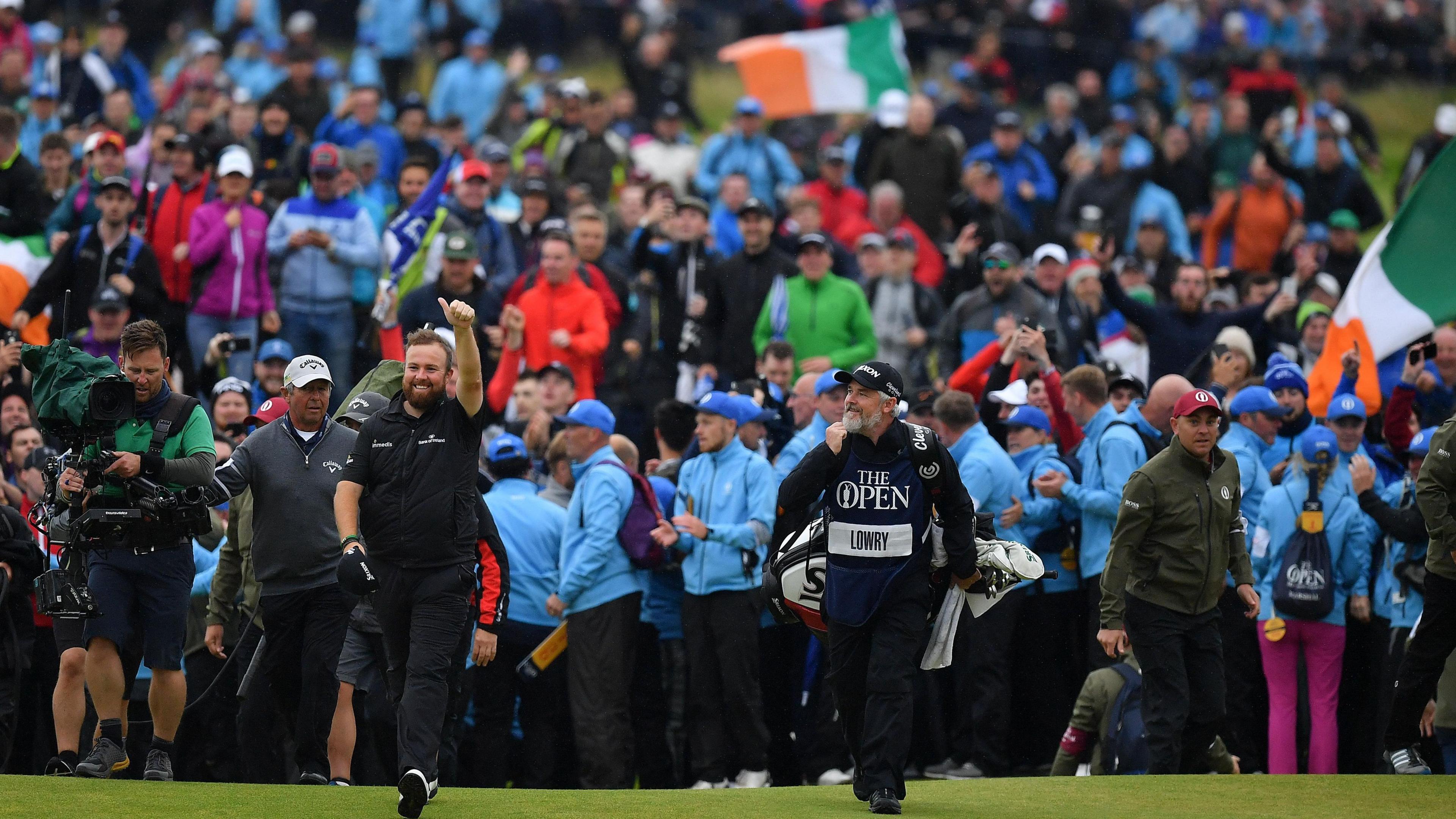 Shane Lowry raises his arm in celebration as he and caddie Bo Martin walk to the 18th green at Royal Portrush