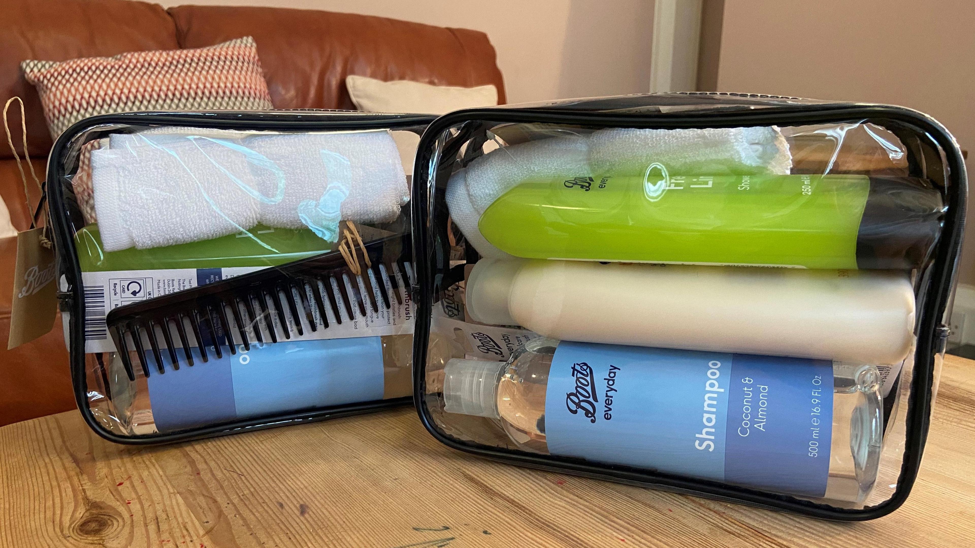 The clear wash bags showing the items inside. bottles of shampoo, combs and flannels are visible. 