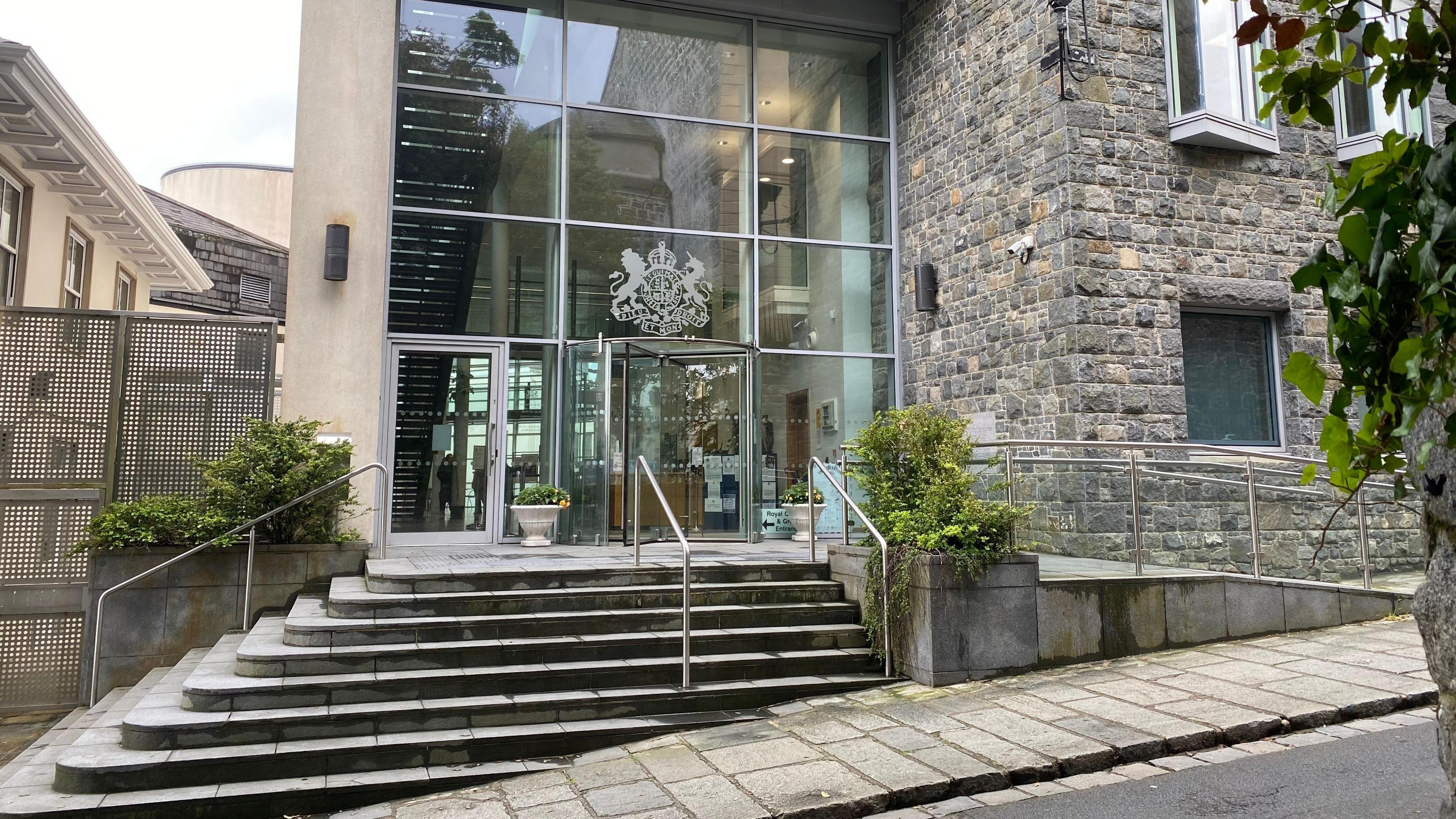 Outside of Guernsey's court building with steps leading up to a revolving glass door