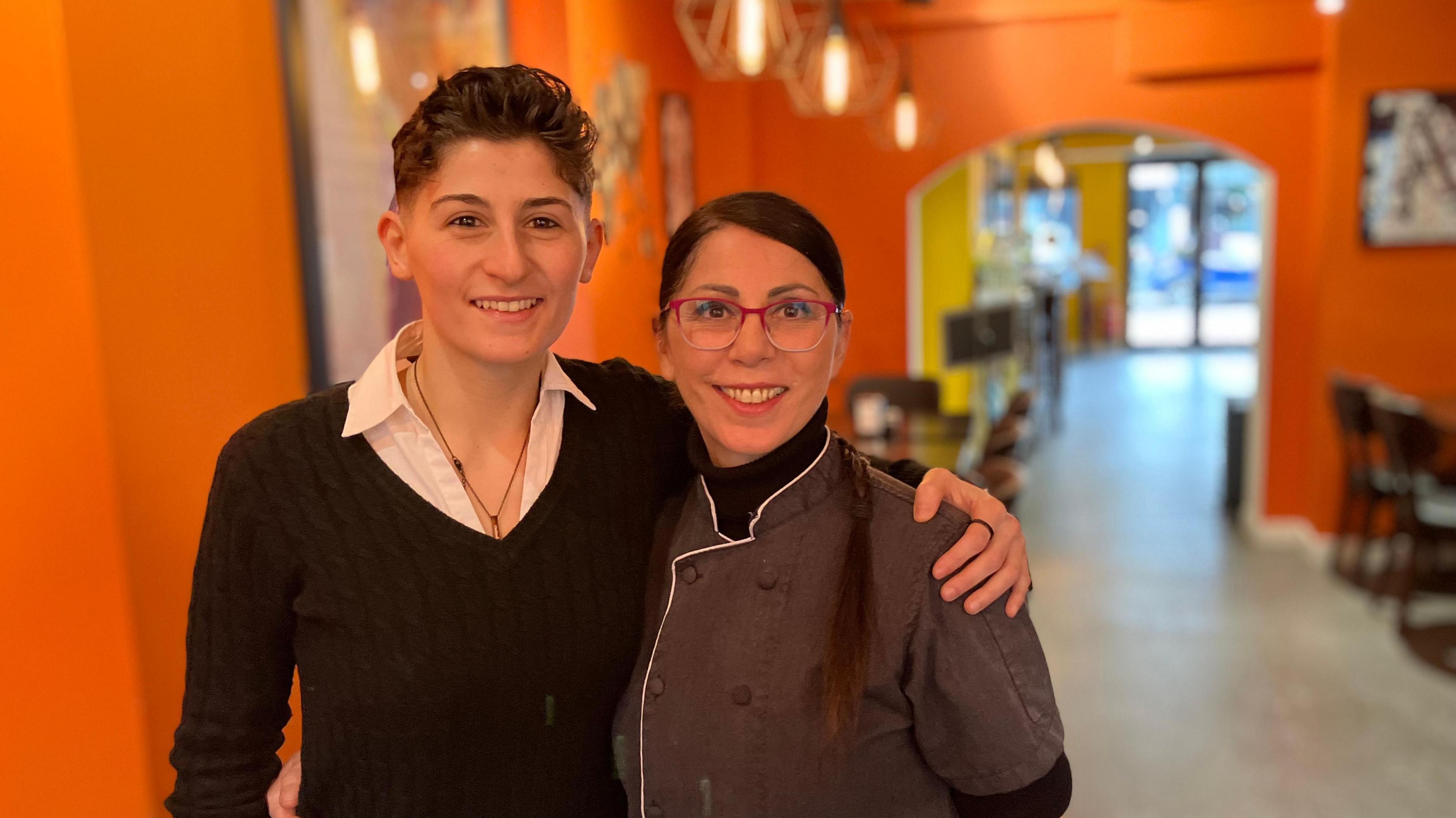 Denise Mosciatti and Rosa Vitagliano, who own La Smorfia on Cowley Road, stand with their arms around each other in their restaurant.