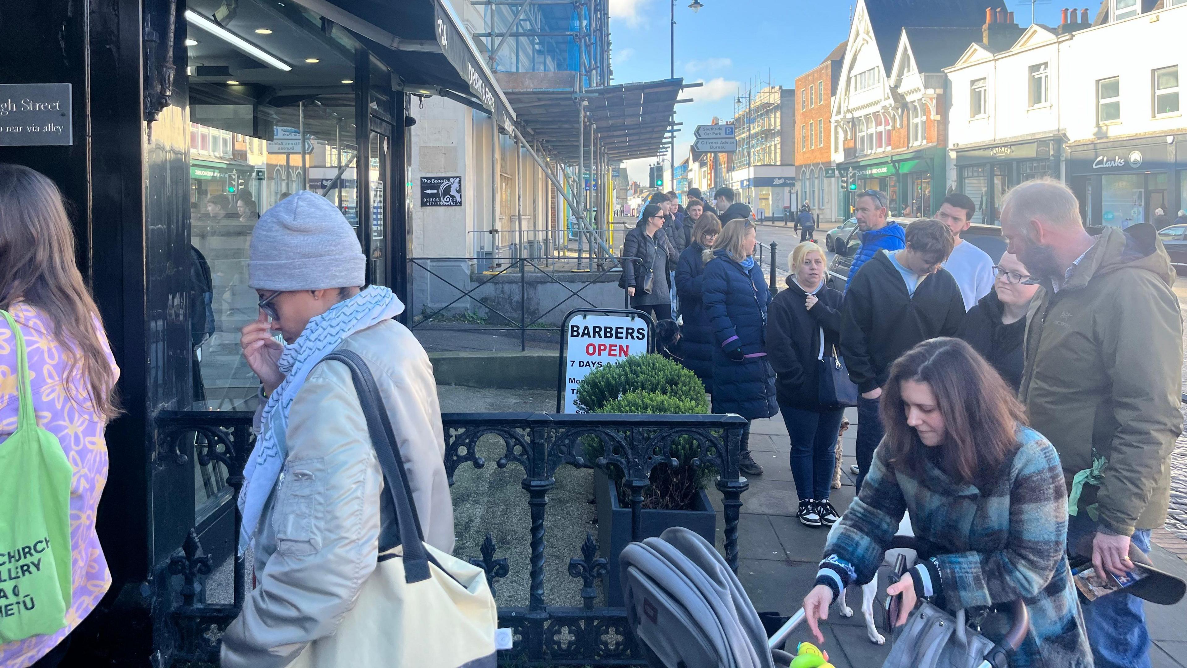 A long queue of people forming outside Coughlans Bakery on Dorking High Street to meet comedian Romesh Ranganathan