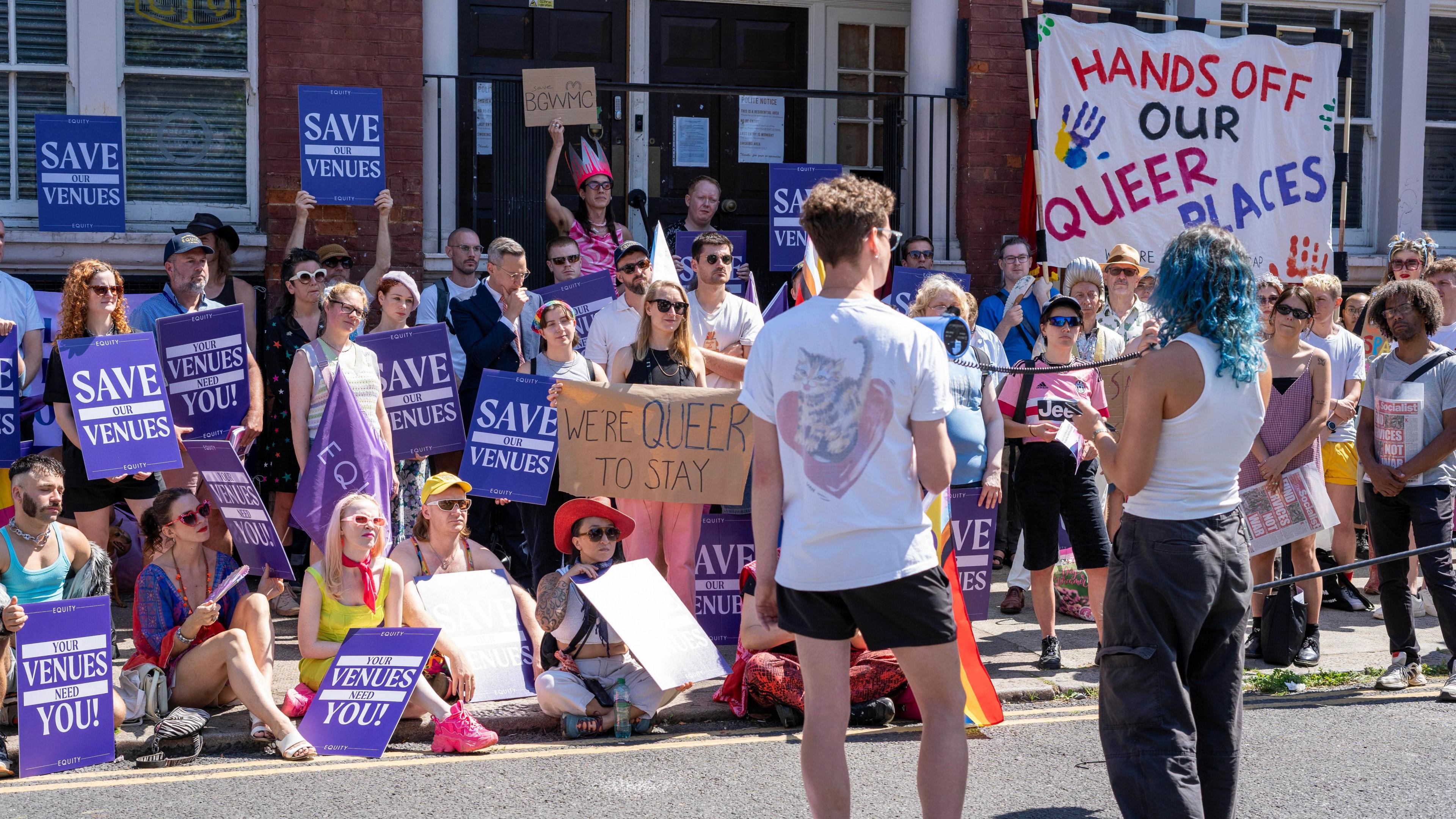 Protesters gather outside Bethnal Green Working Men's Club with signs reading 'save our venues' and 'hands off our queer places', taken in July