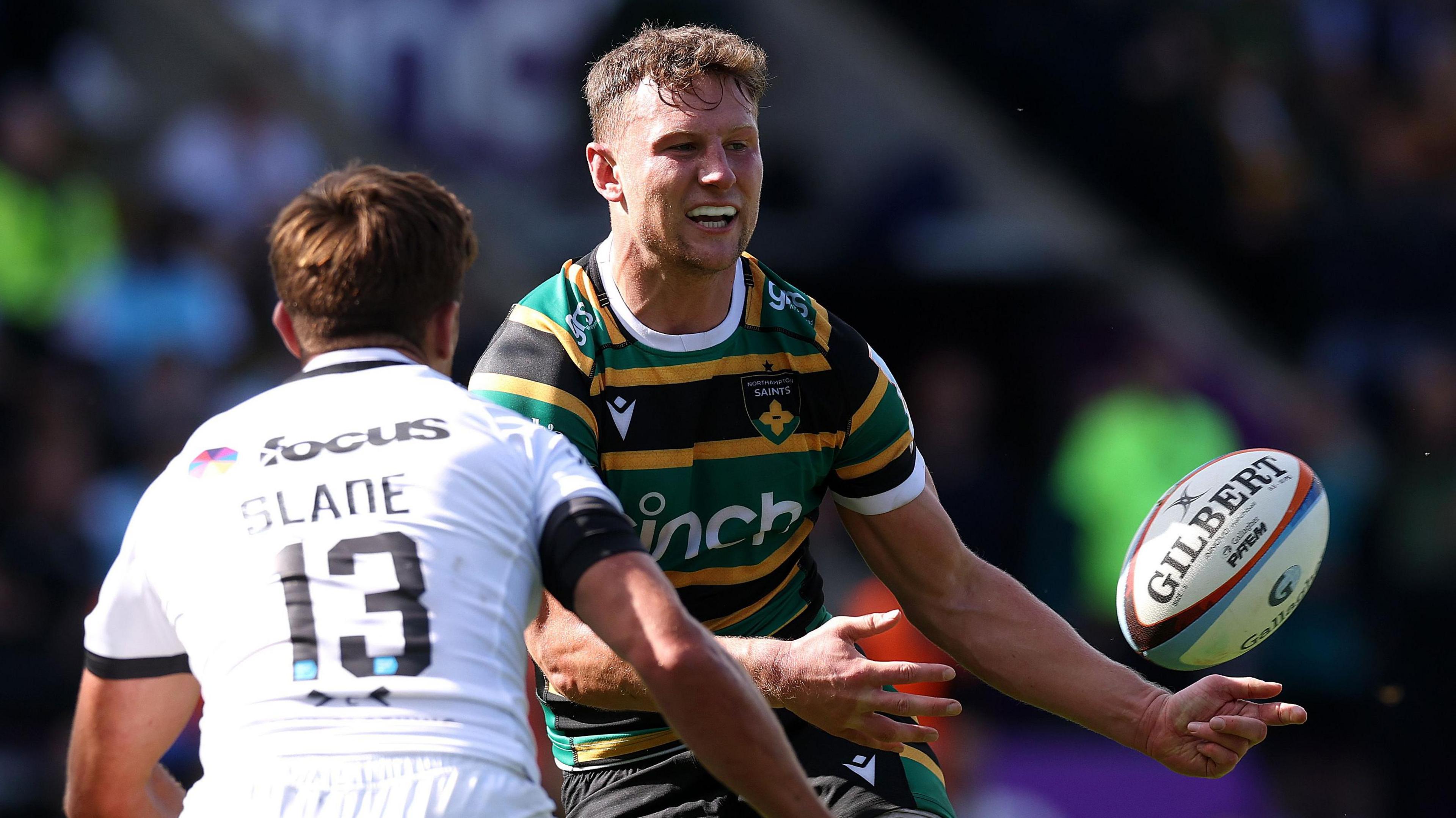 Northampton's Fraser Dingwall, faced by Henry Slade of Exeter, passes the ball to a team-mate