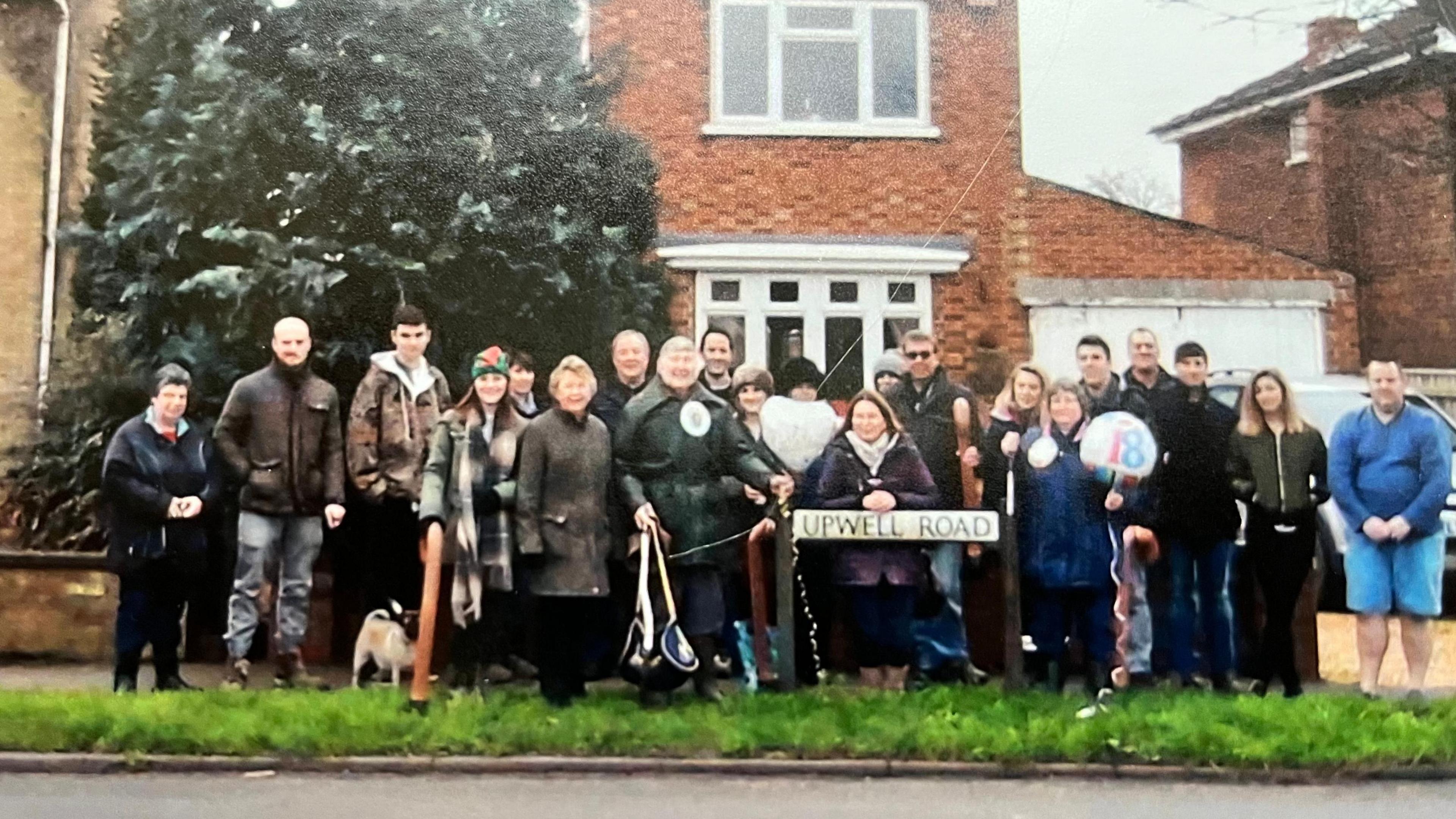 A group of 21 people and a dog gather outside a house on Upwell Road in March where Mr Bedford lived as a child, this picture marks the 50th walk undertaken on Christmas Day 2015.