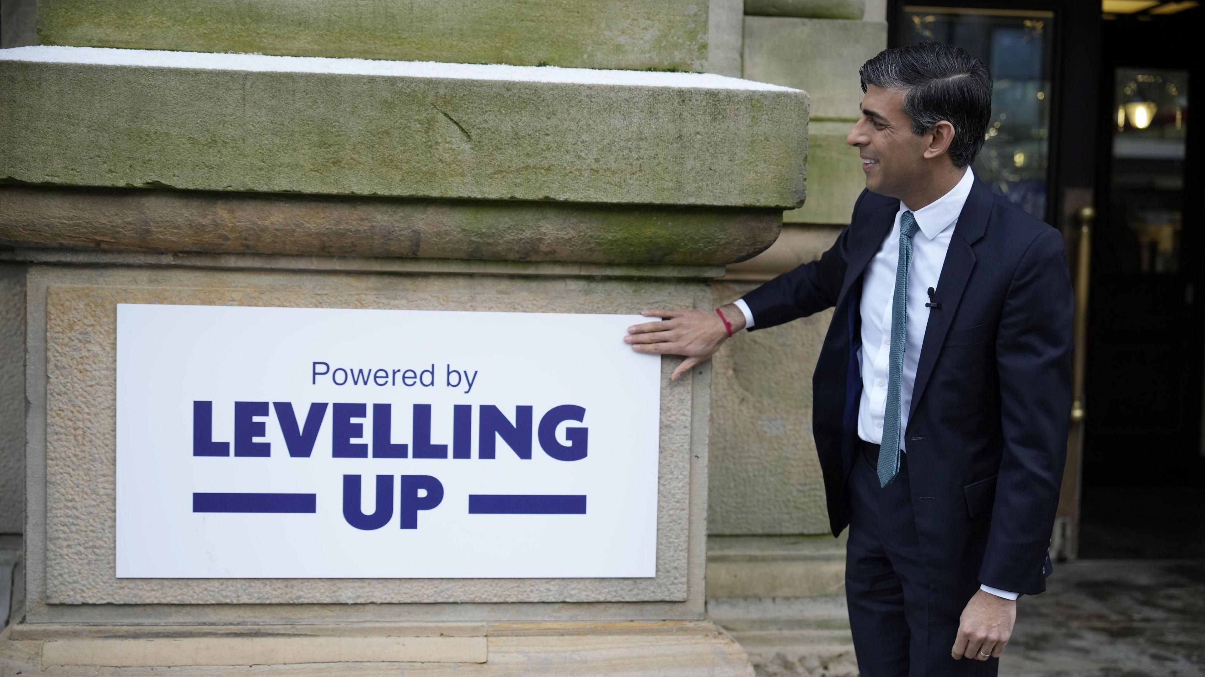 Rishi Sunak in January with a sign reading Powered by Levelling Up, on a community project visit to Accrington Market Hall in Lancashire