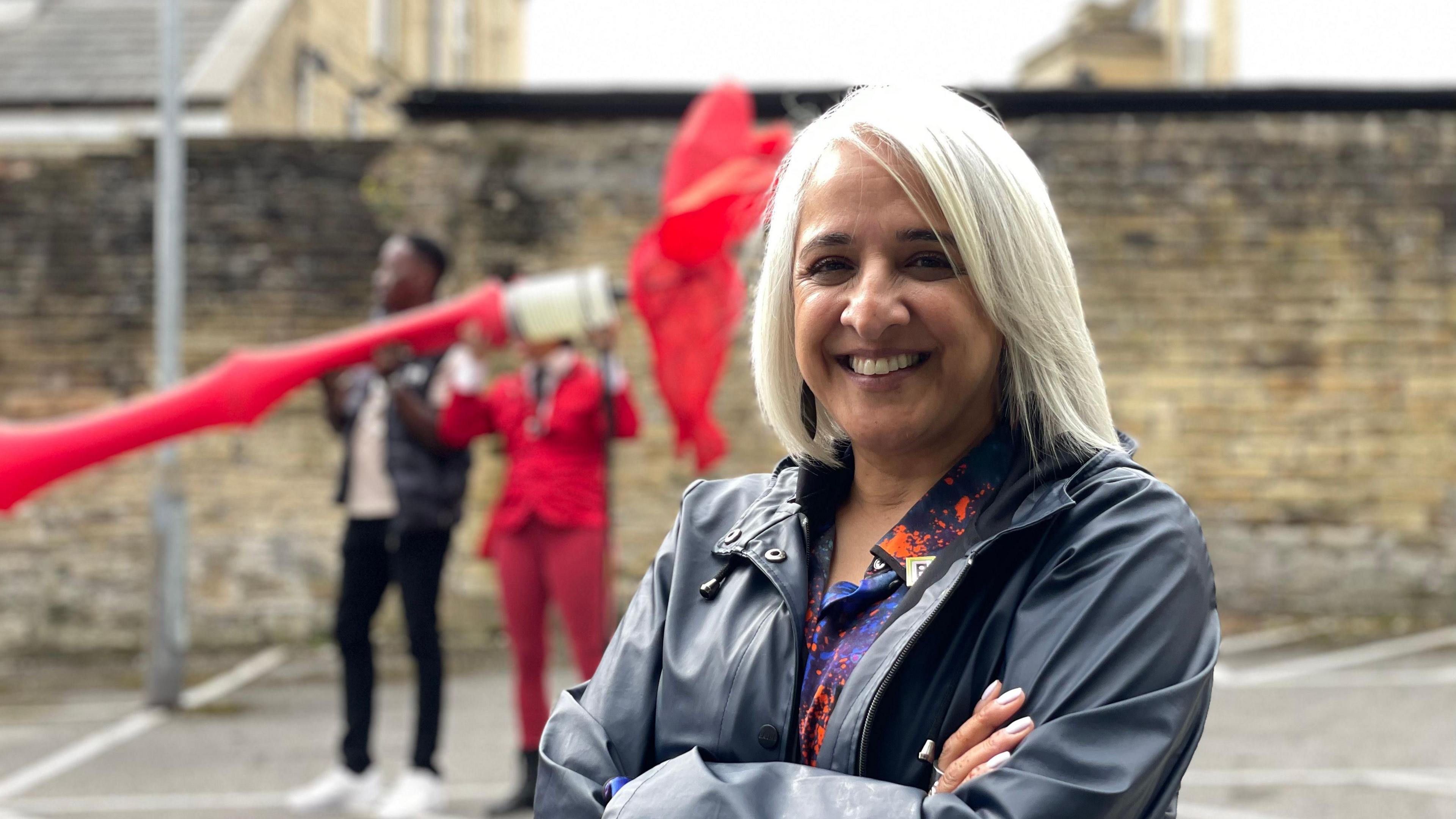 Shanaz Gulzar, creative director of Bradford 2025, standing and smiling with her arms folded