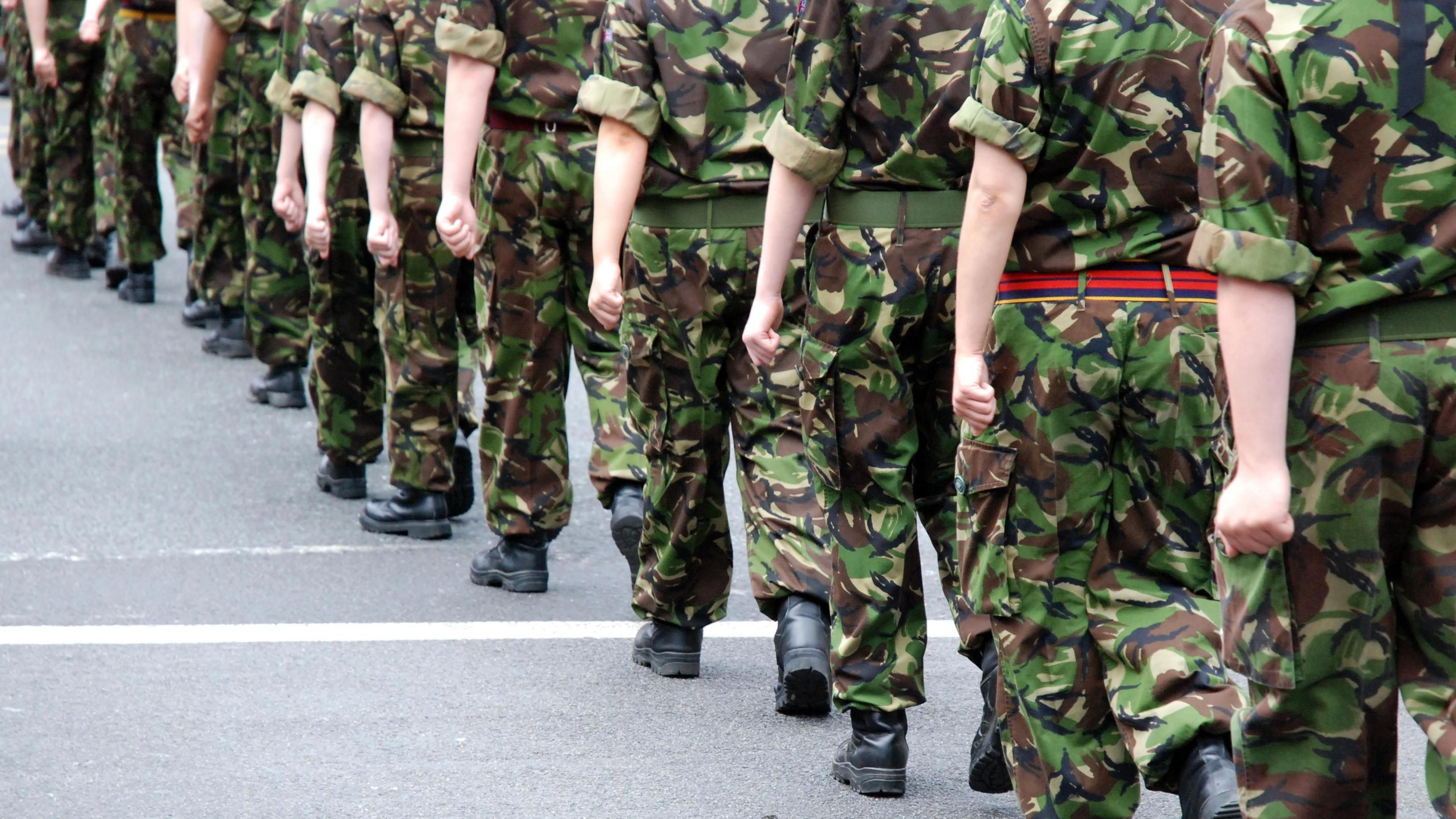 Close up shot of the legs of British soldiers who are in uniform and marching through the street