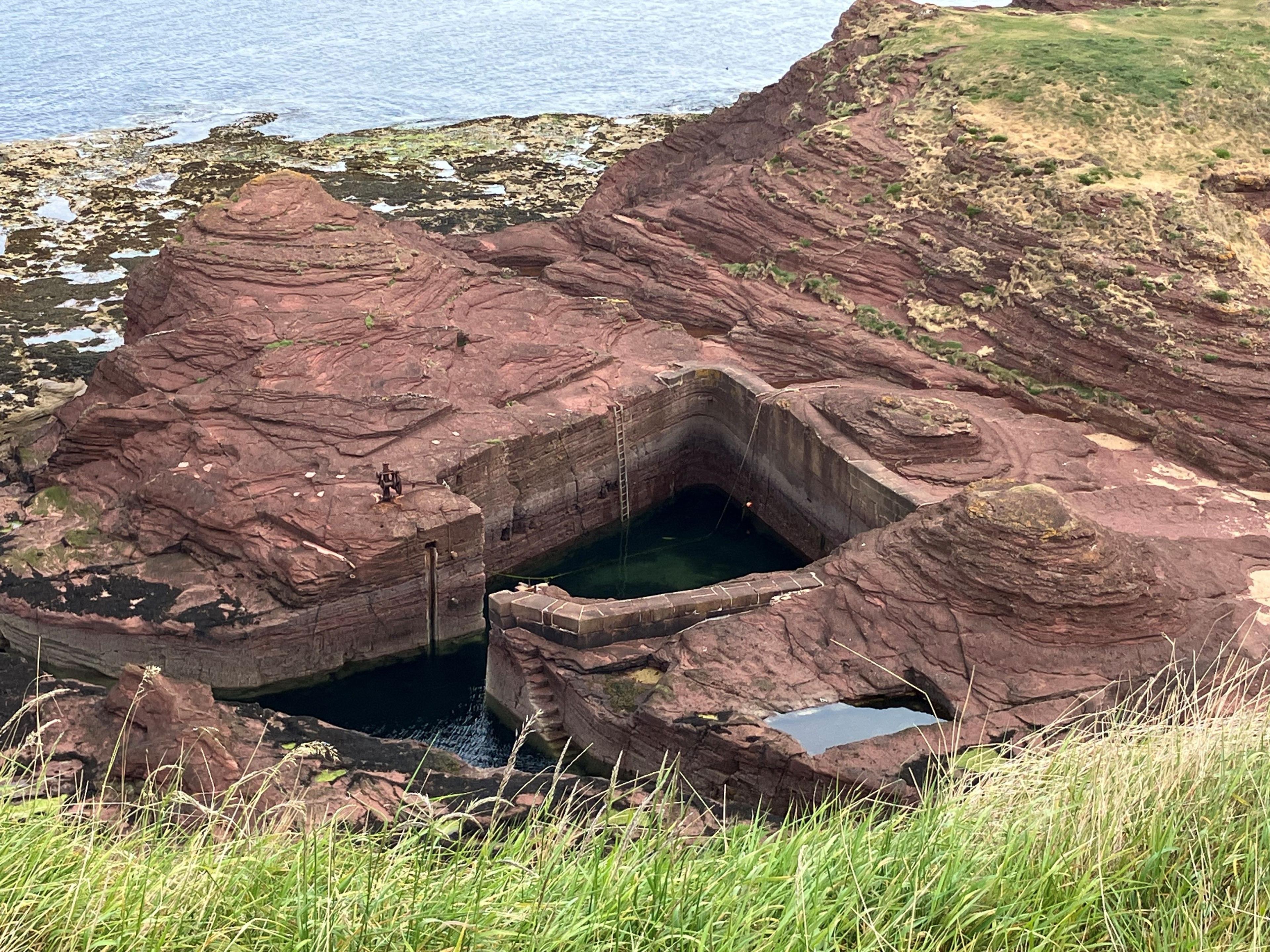 Red rock with a small square cut out of it in the middle. There is a very small entrance.