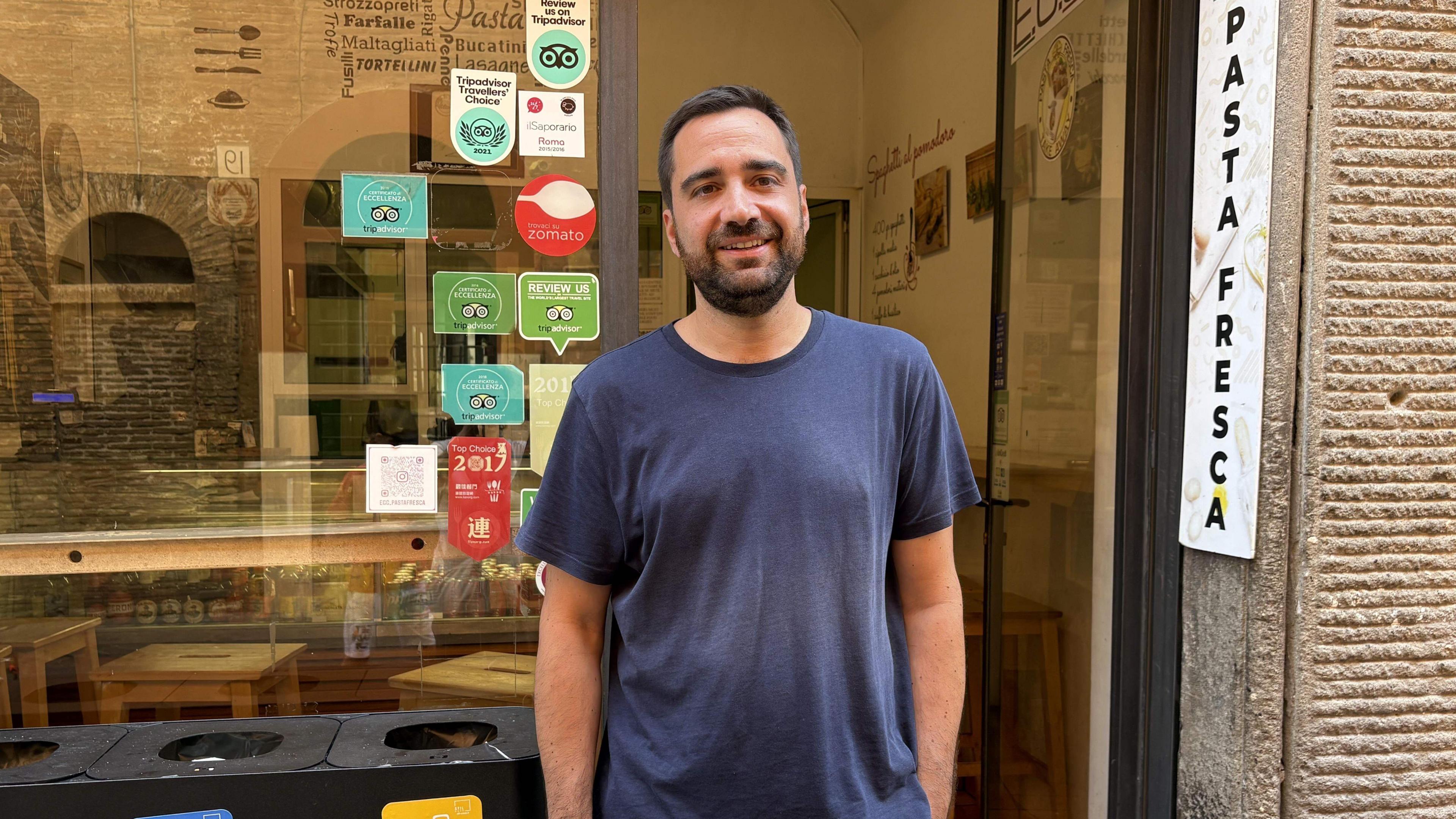 a man stands in front of a pasta shop