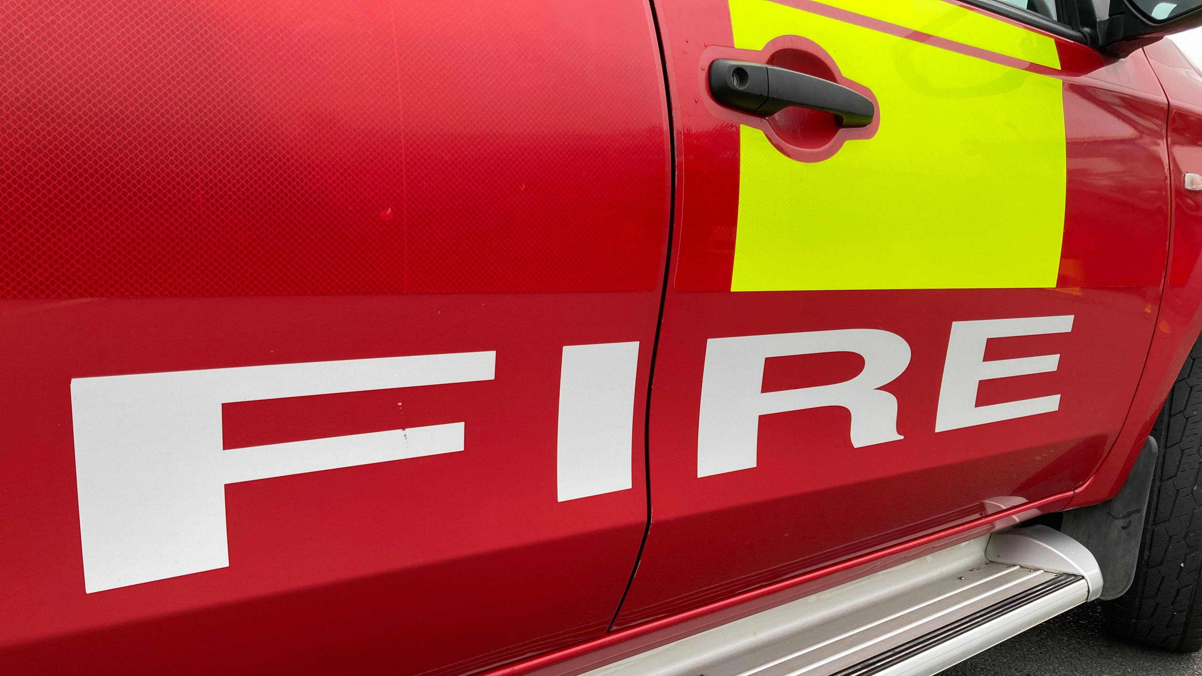 A close-up of the side of a red fire service vehicle.