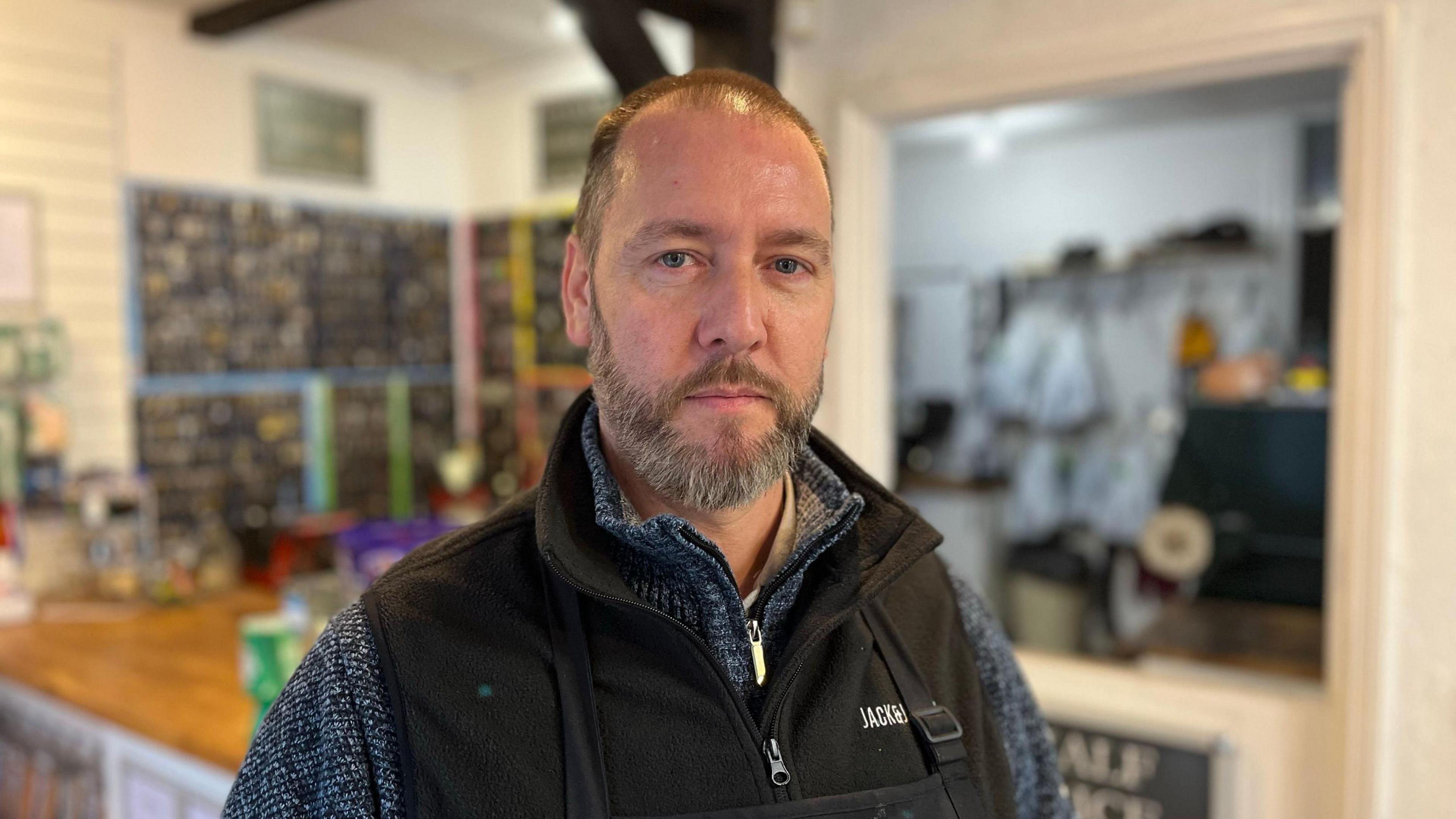 MAtt Betts stood in his shoe repair shop with a wall of keys behind him