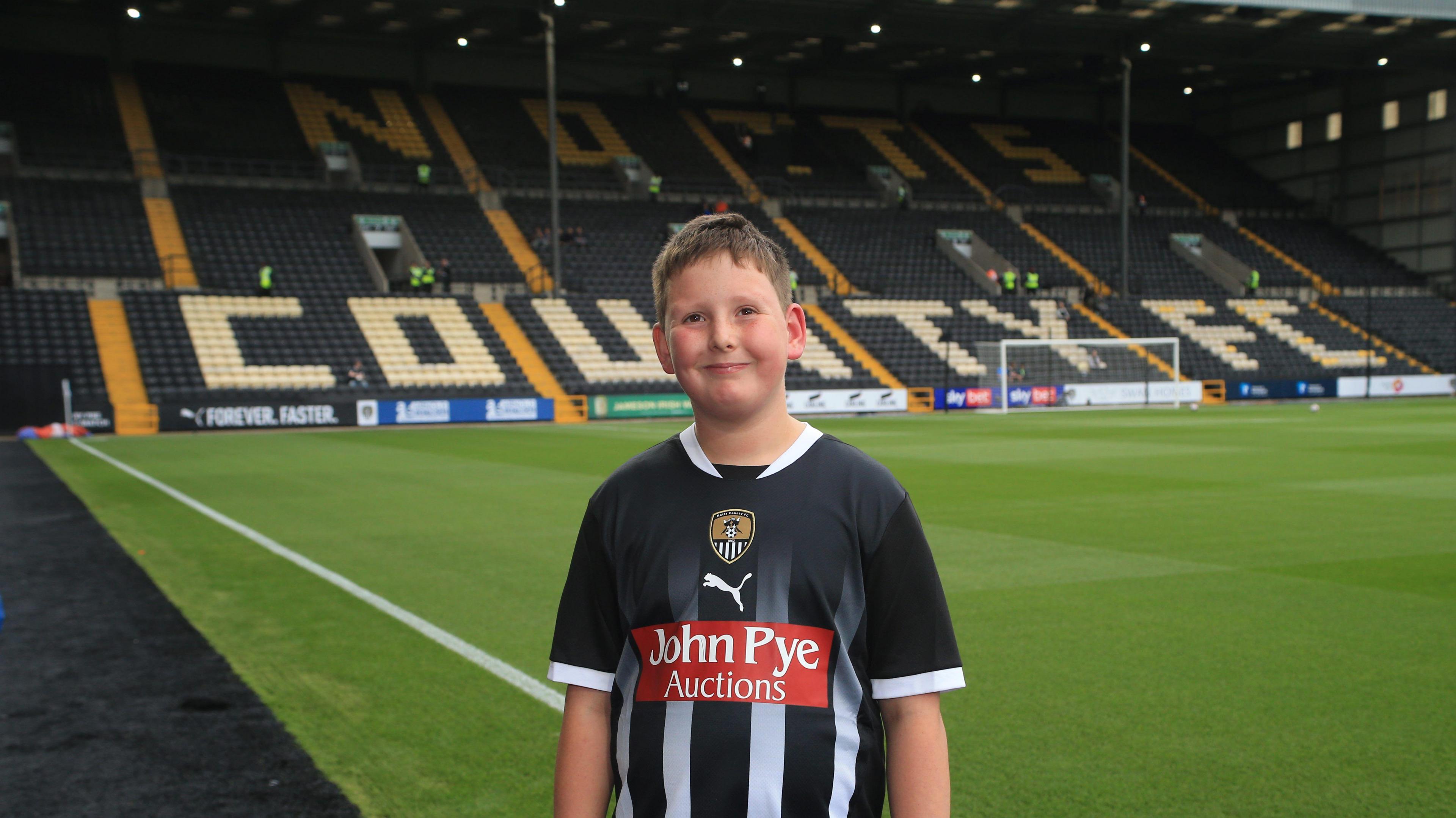 A child is pictured wearing a black and white-striped Notts County home shirt in the club's Meadow Lane stadium
