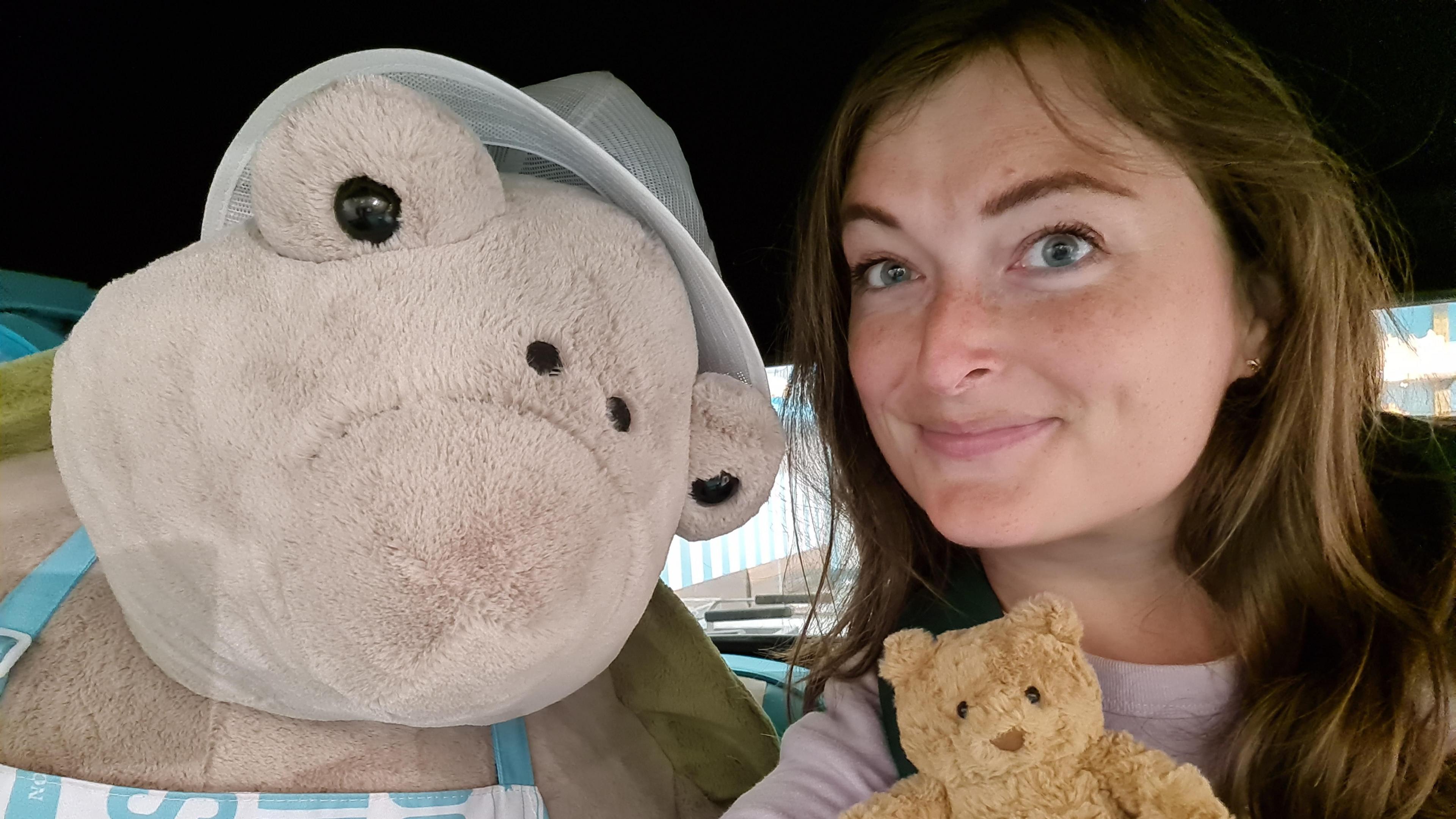 Amanda Hope poses next to a giant Jellycat soft toy turtle and holds one of the brand's famous brown teddy bears