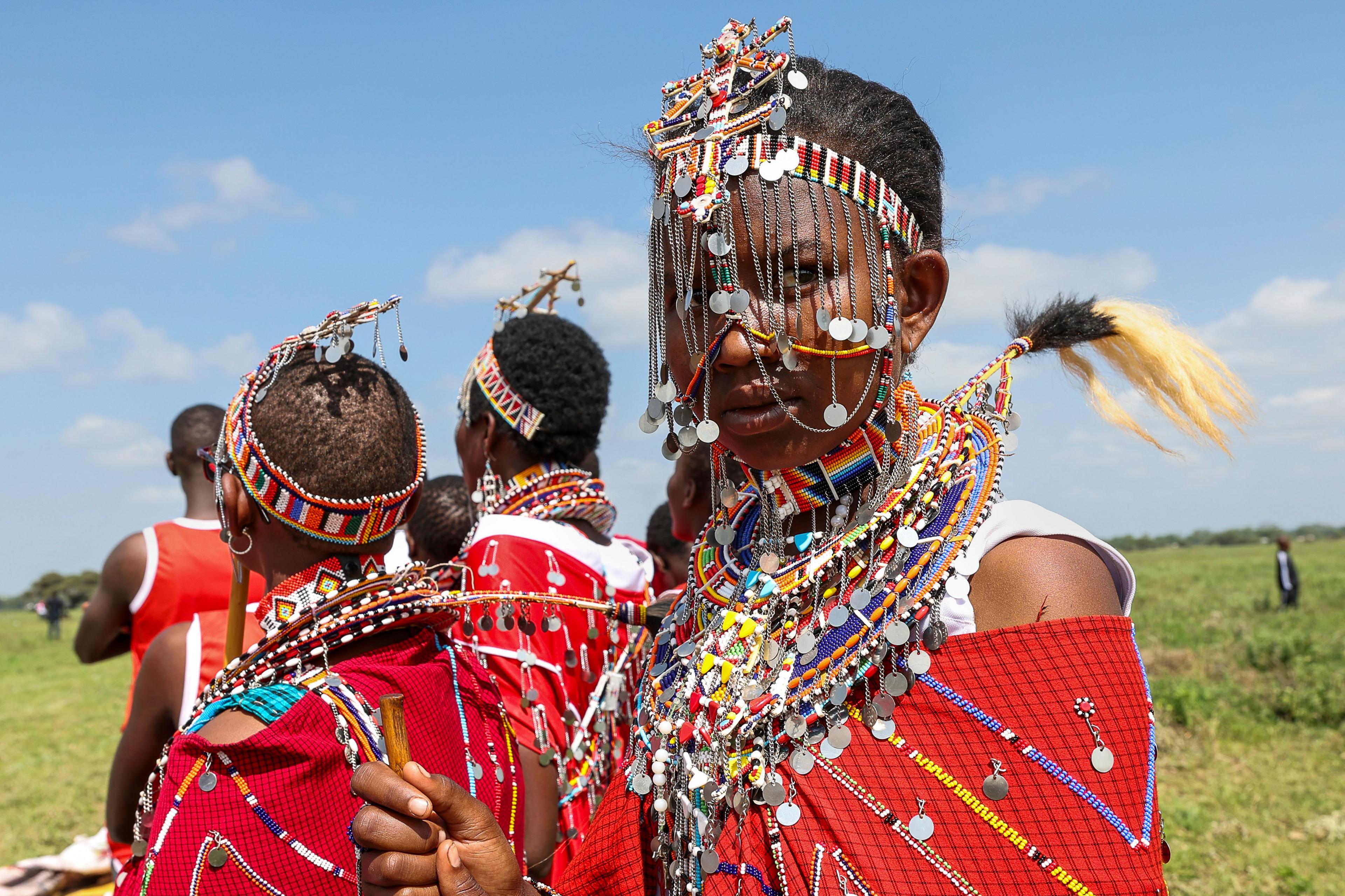 A traditional Maasai woman wearing the traditional attire looks at the camera as she attends a social sporting event called the Maasai Olympics in Kajiado, Kenya - Saturday 14 December