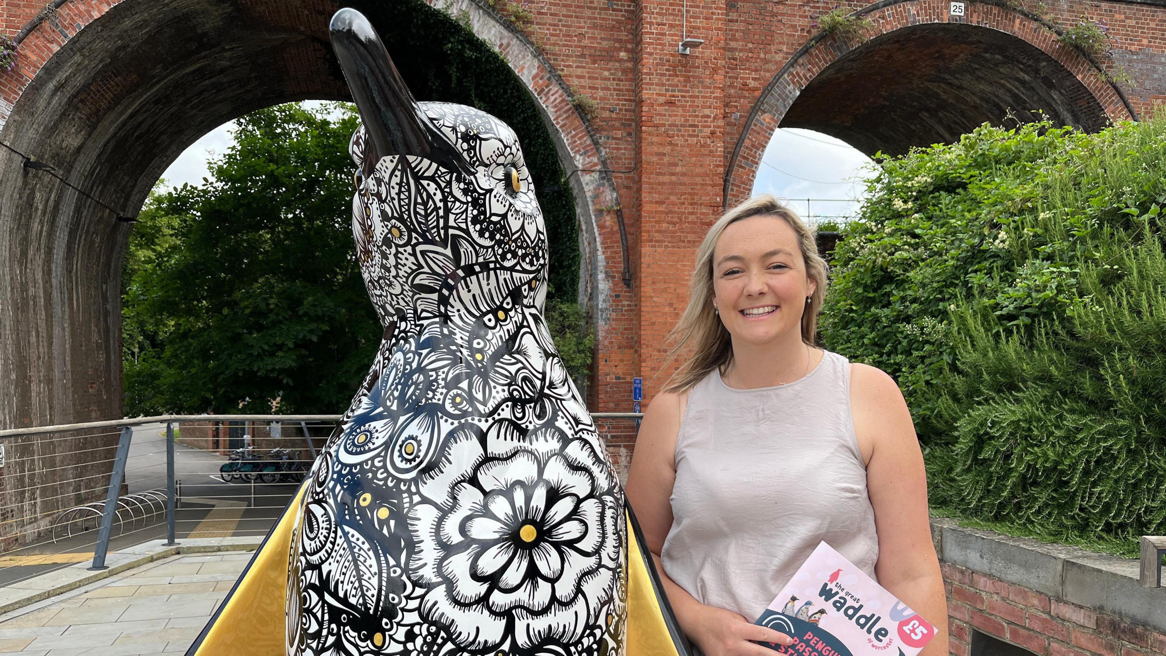 A woman stood next to a penguin sculpture