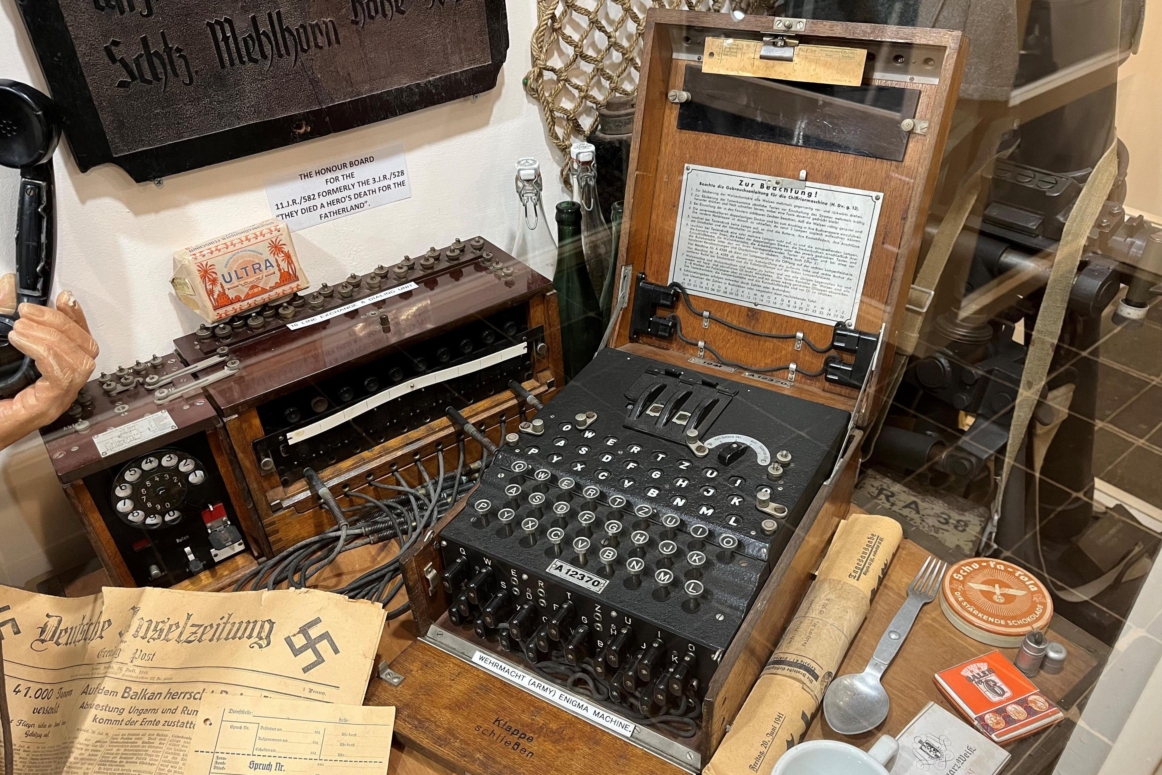 An Engima machine on display in a museum surrounded by other items relating to the German Occupation of Jersey.