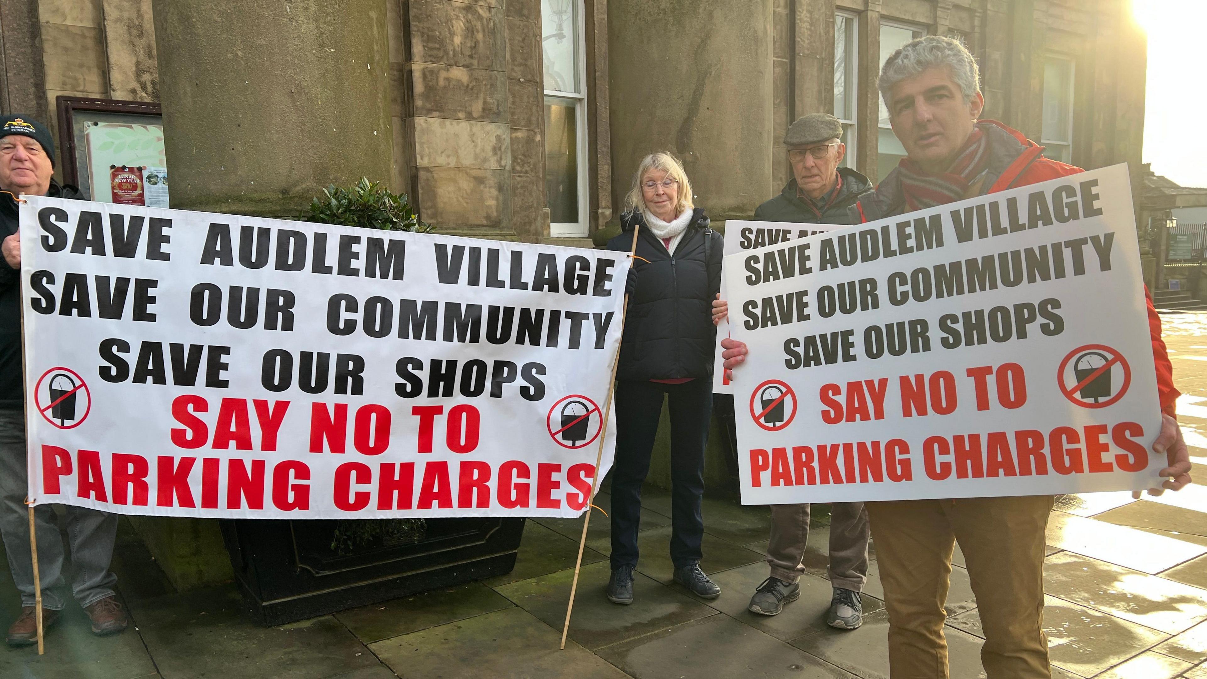 Protestors outside Macclesfield town hall. They are holding signs saying no to parking charges in Audlem.