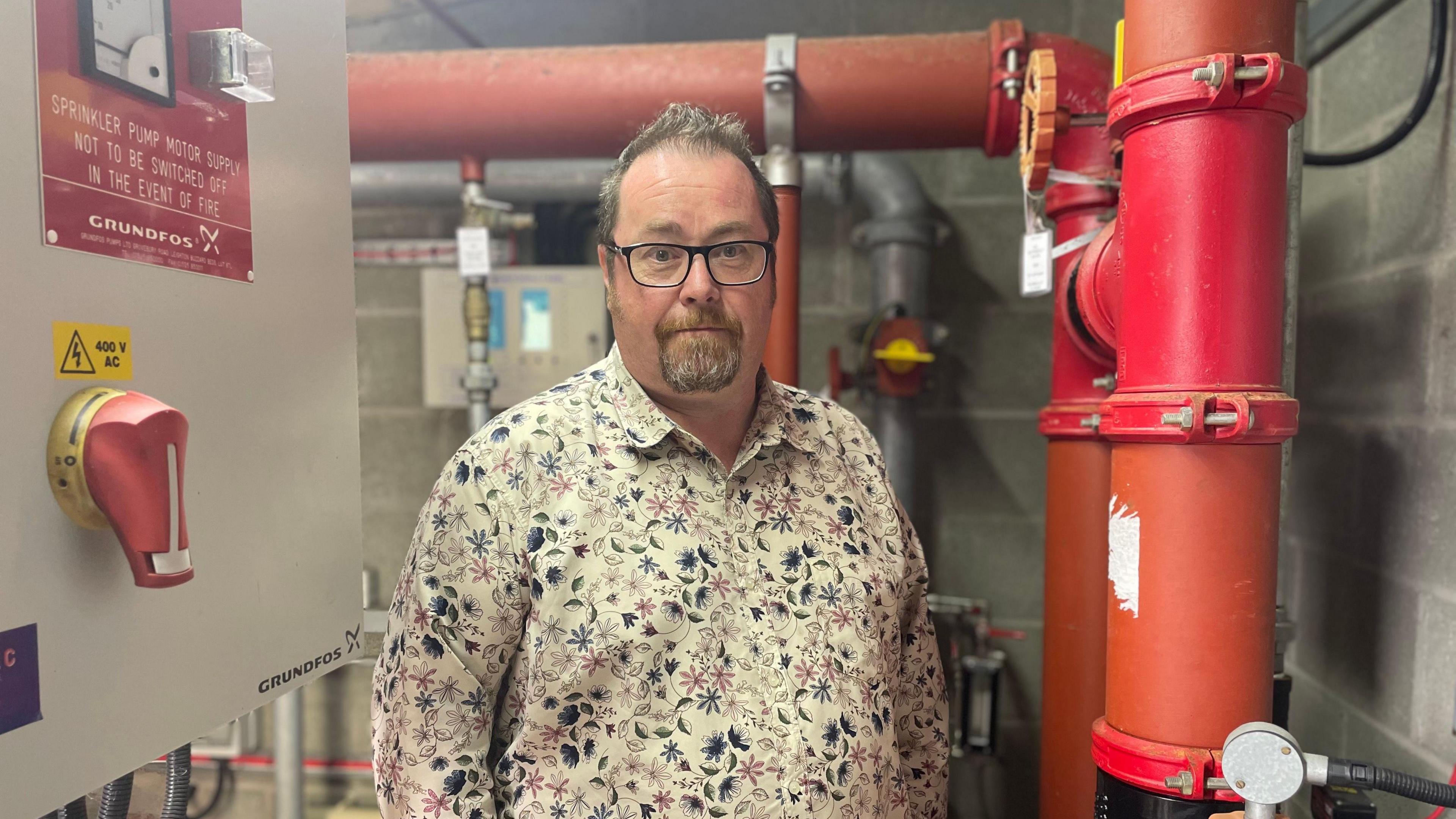 Head teacher Gareth Lewis standing in front of the school sprinkler system