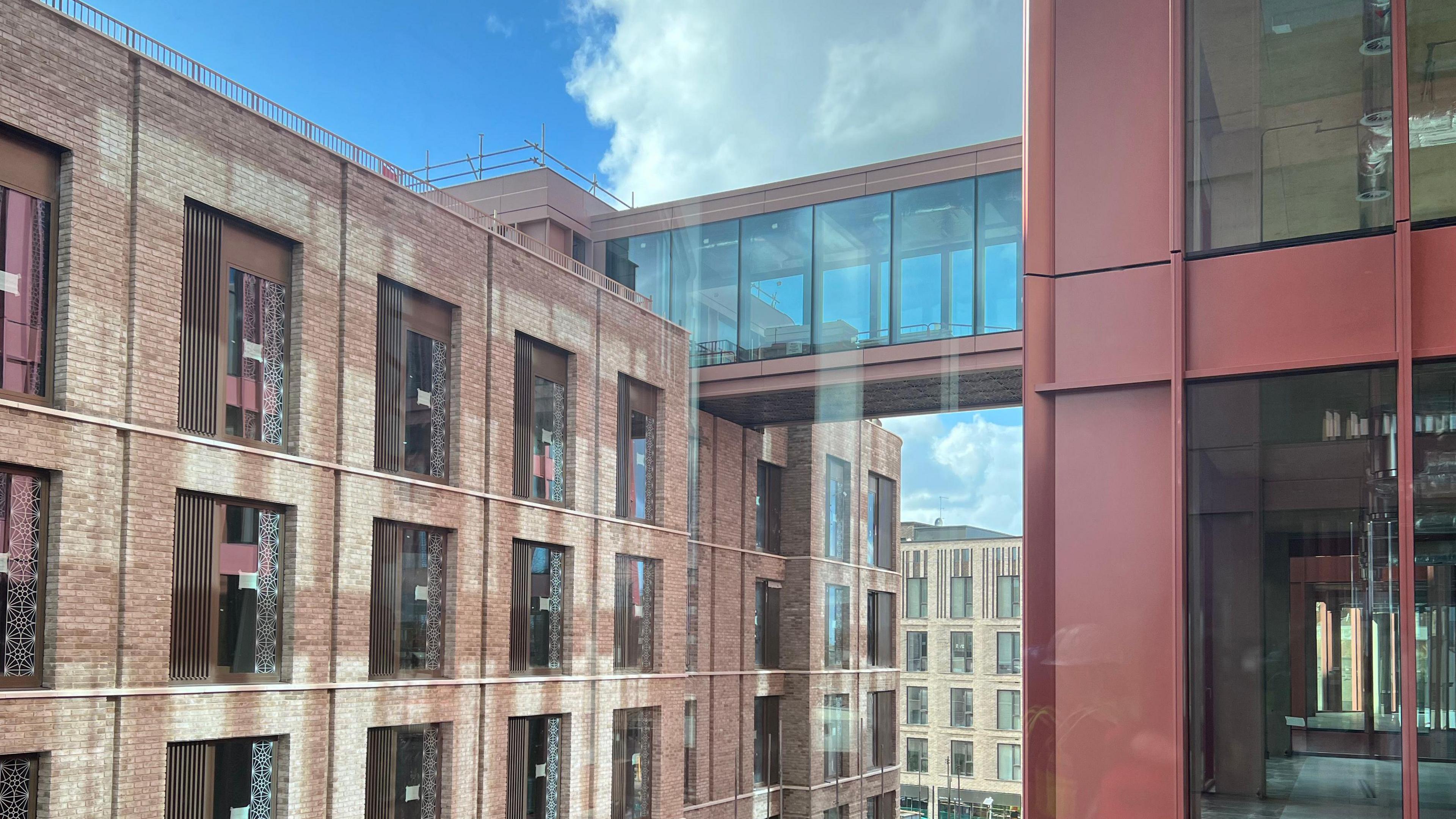 The bridge which connects the two buildings at the Forum in Gloucester. The facade is red and the windows are full length.