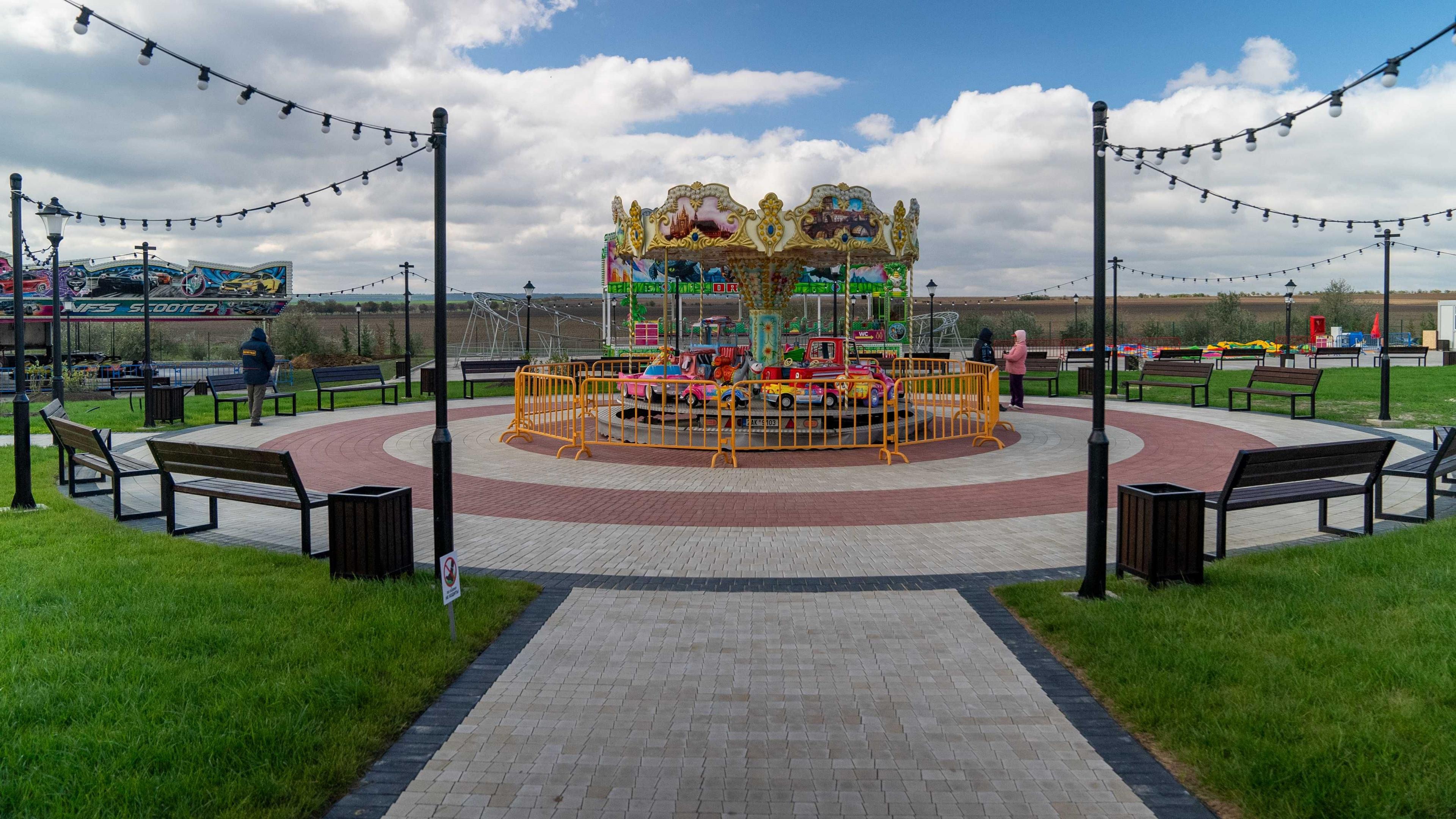 A picture of a small children's merry go round with cars in Gagauziyaland. The park looks very new, but there is hardly anyone there. It looks empty