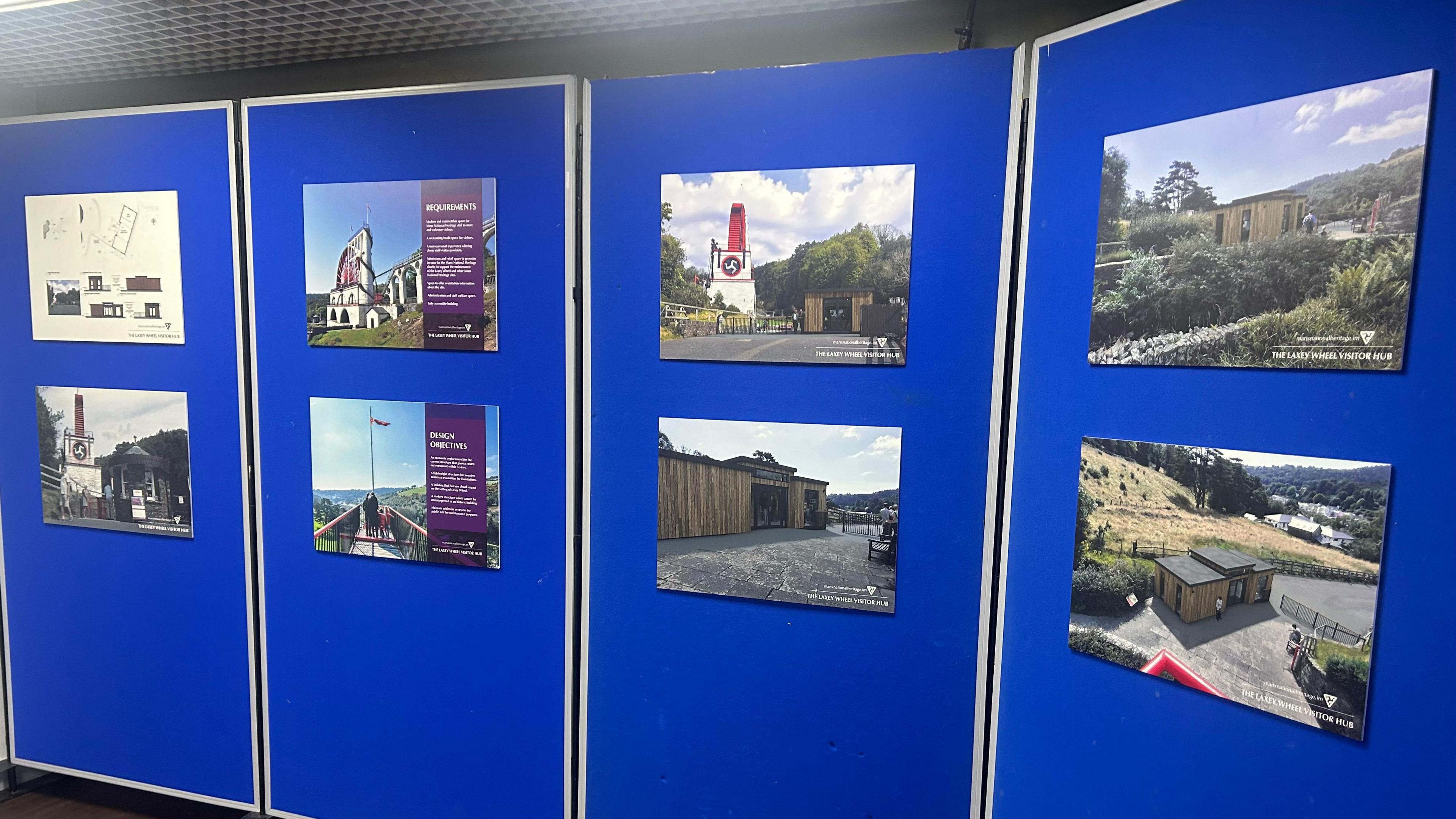 Blue display boards with images of the Laxey Wheel and the proposed visitor hub, a wooden small building.