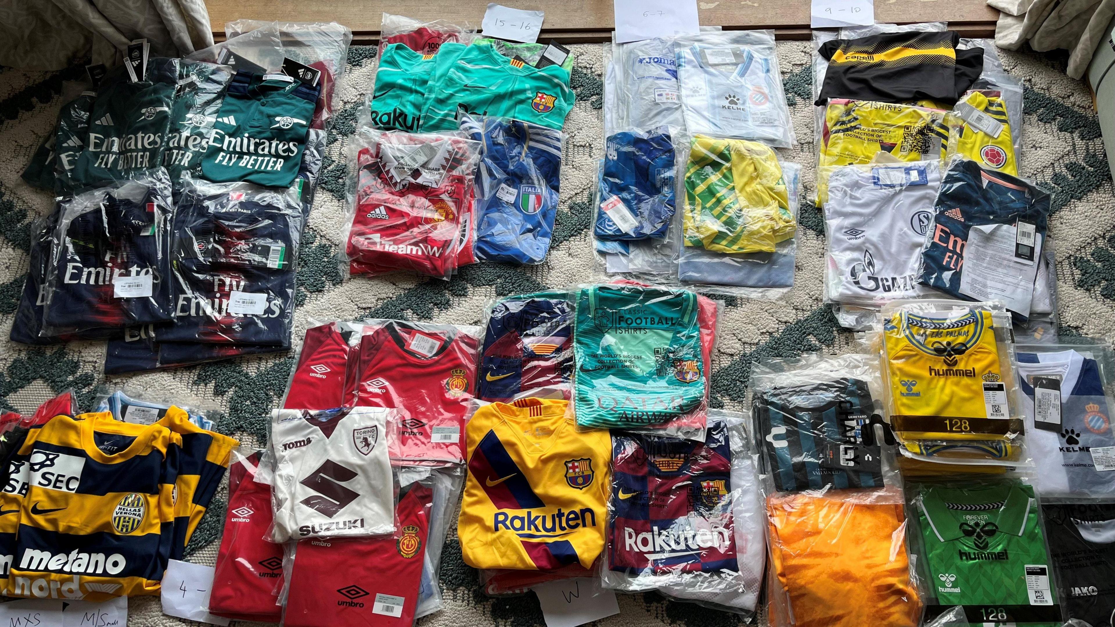 Loads of different coloured football shirts laying on the floor of a living room.