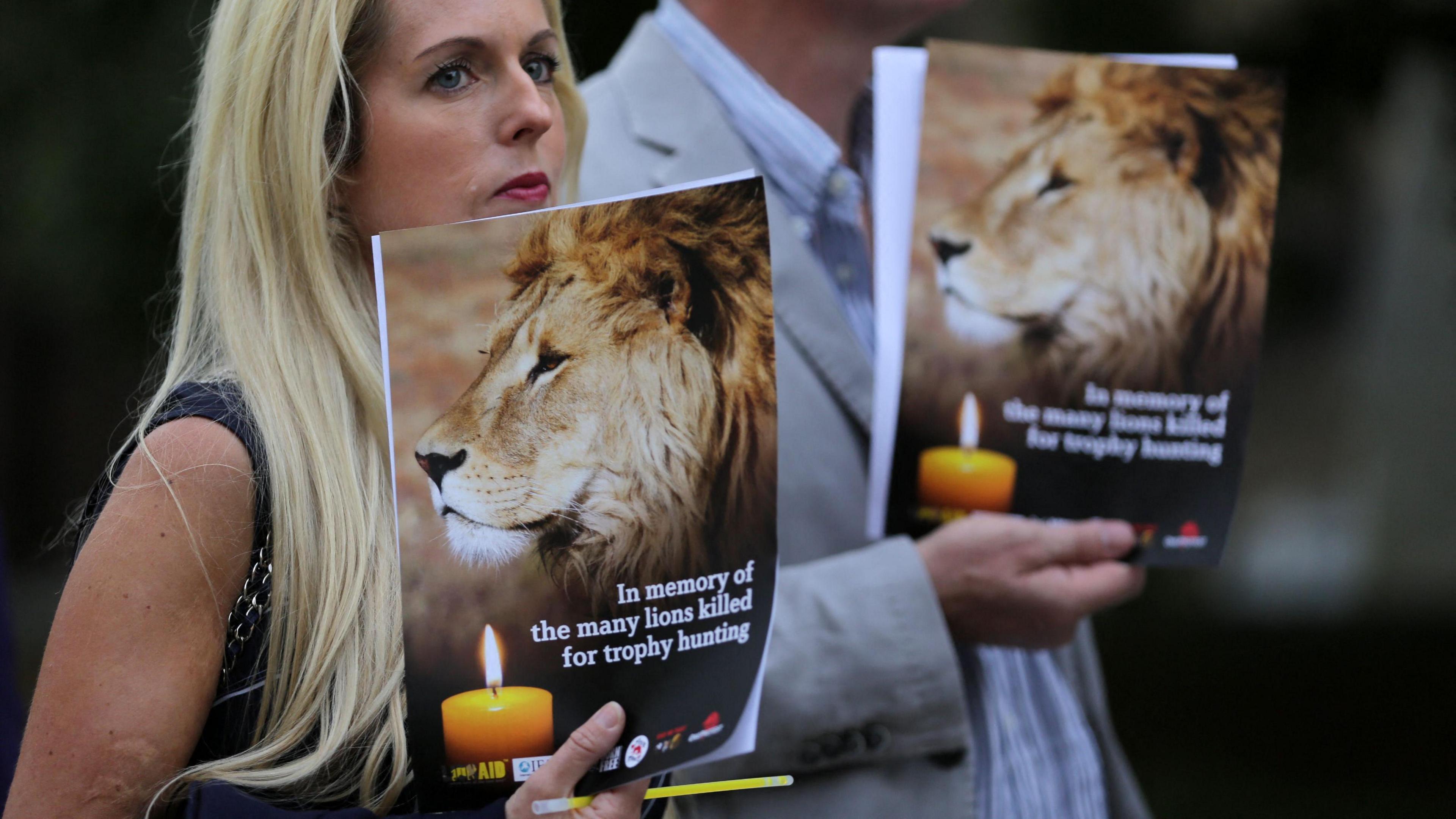 People hold candles and pamphlets shows an image of Cecil the lion at a vigil in central London on July 30, 2016.