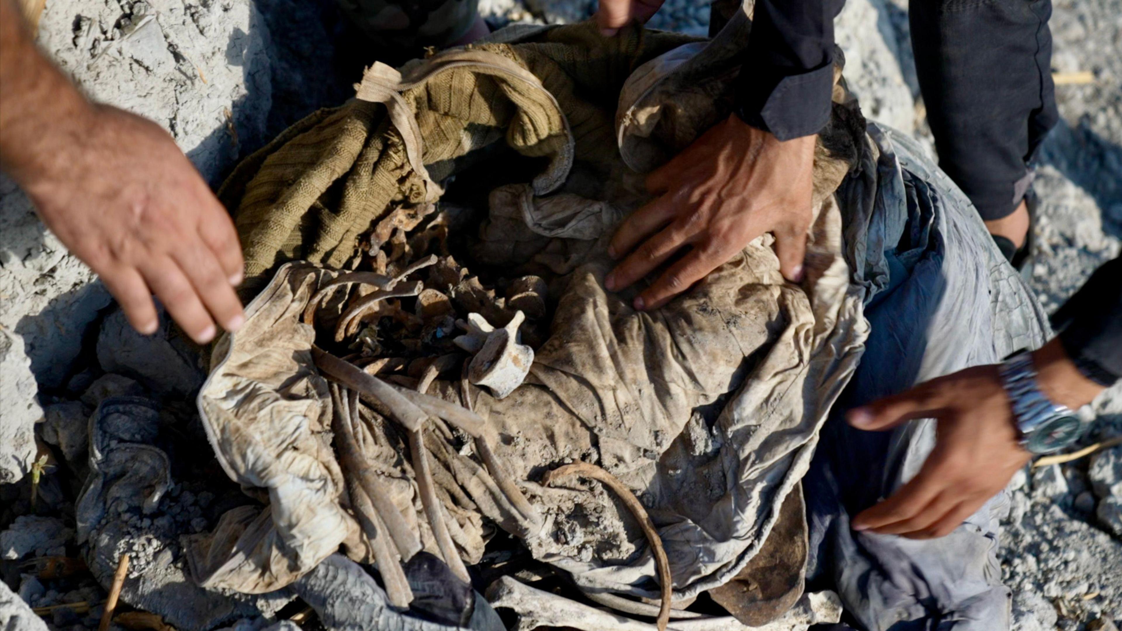 Close up view of hands of people looking at a bundle of cloth and ribs and vertebrae.
