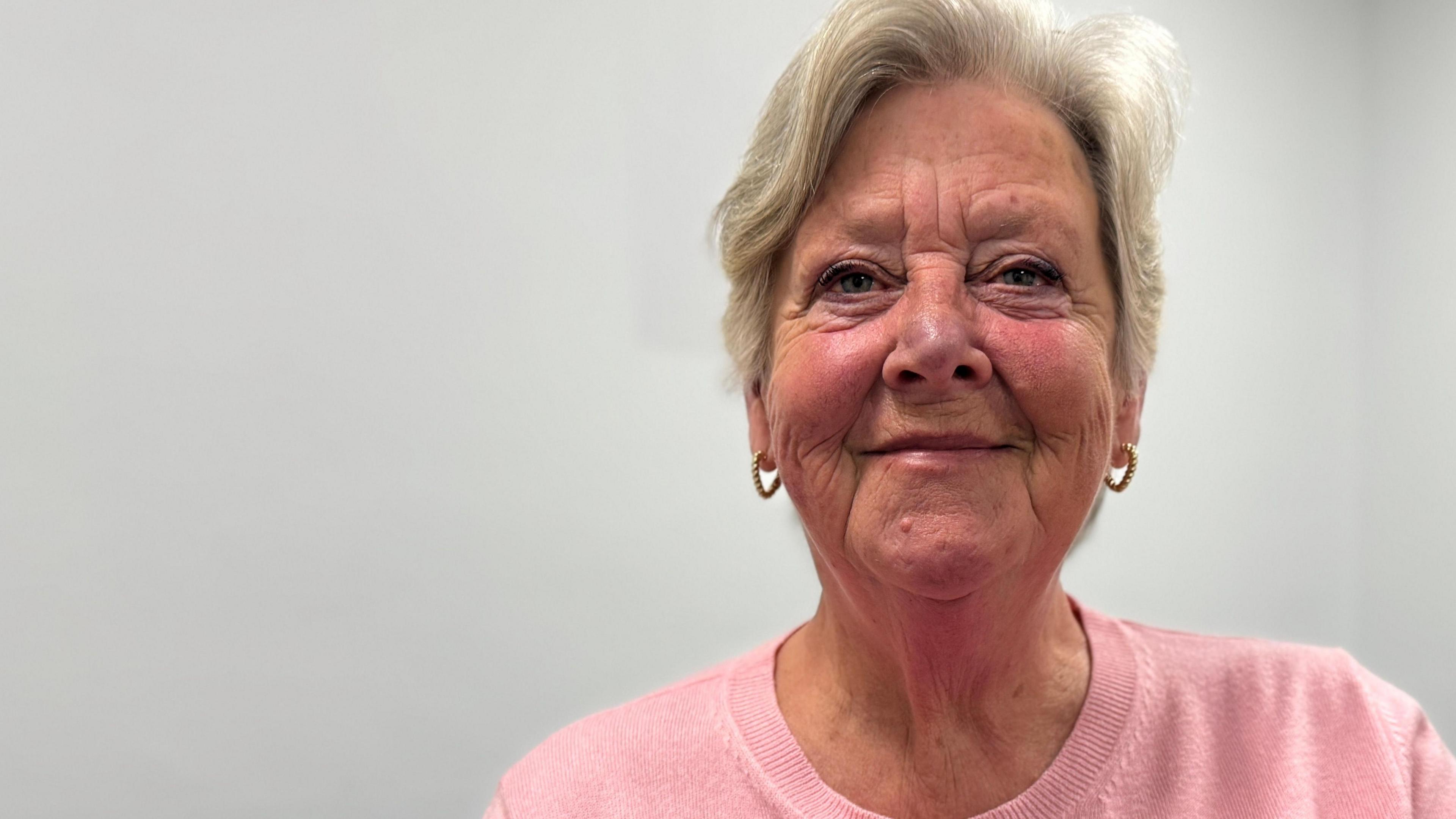 A head and shoulders photograph of Councillor Virginia Moran who is wearing a pink top and a red poppy