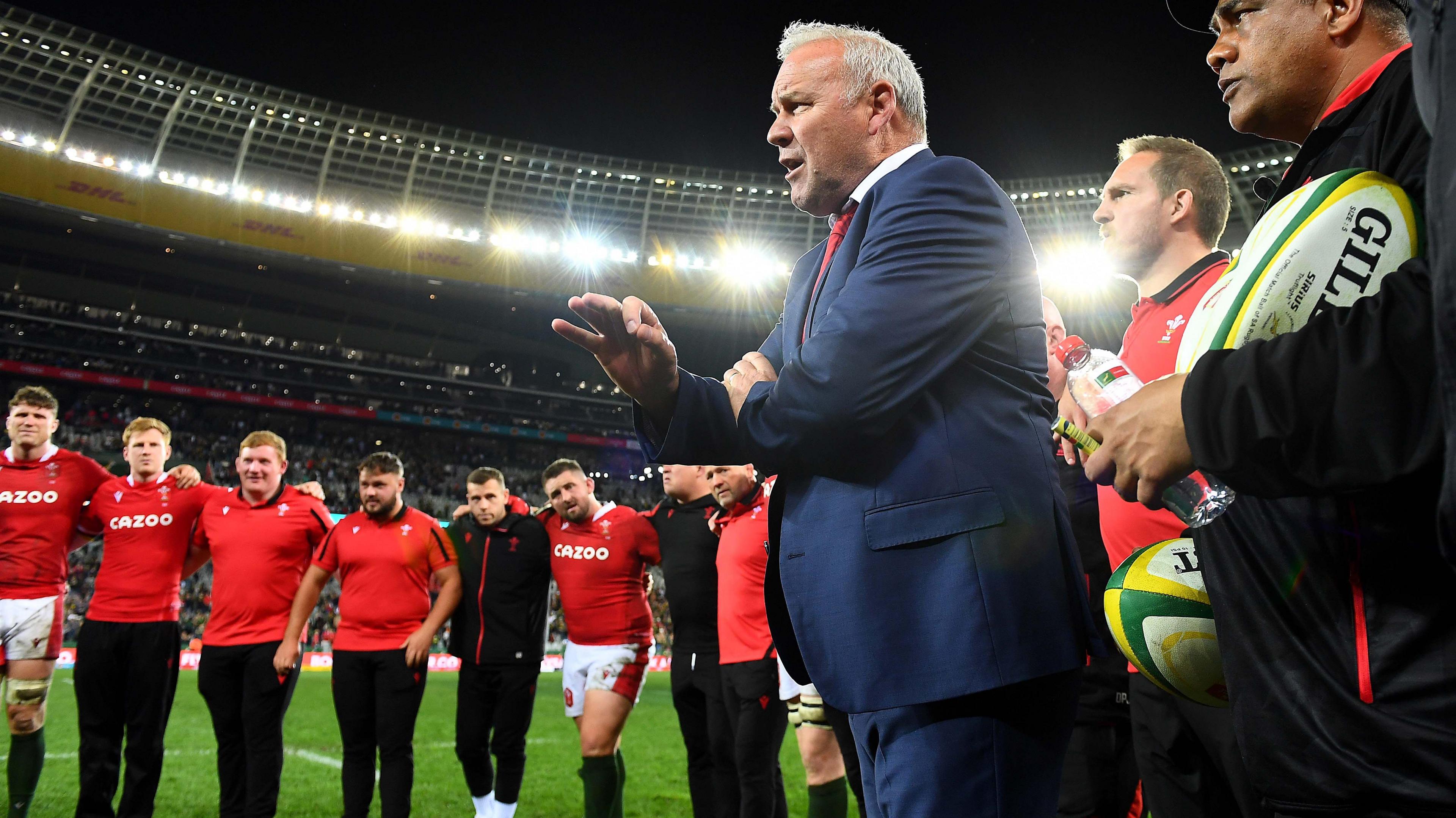 Wayne Pivac a tîm Cymru mewn cylch ar y cae yn Cape Town.