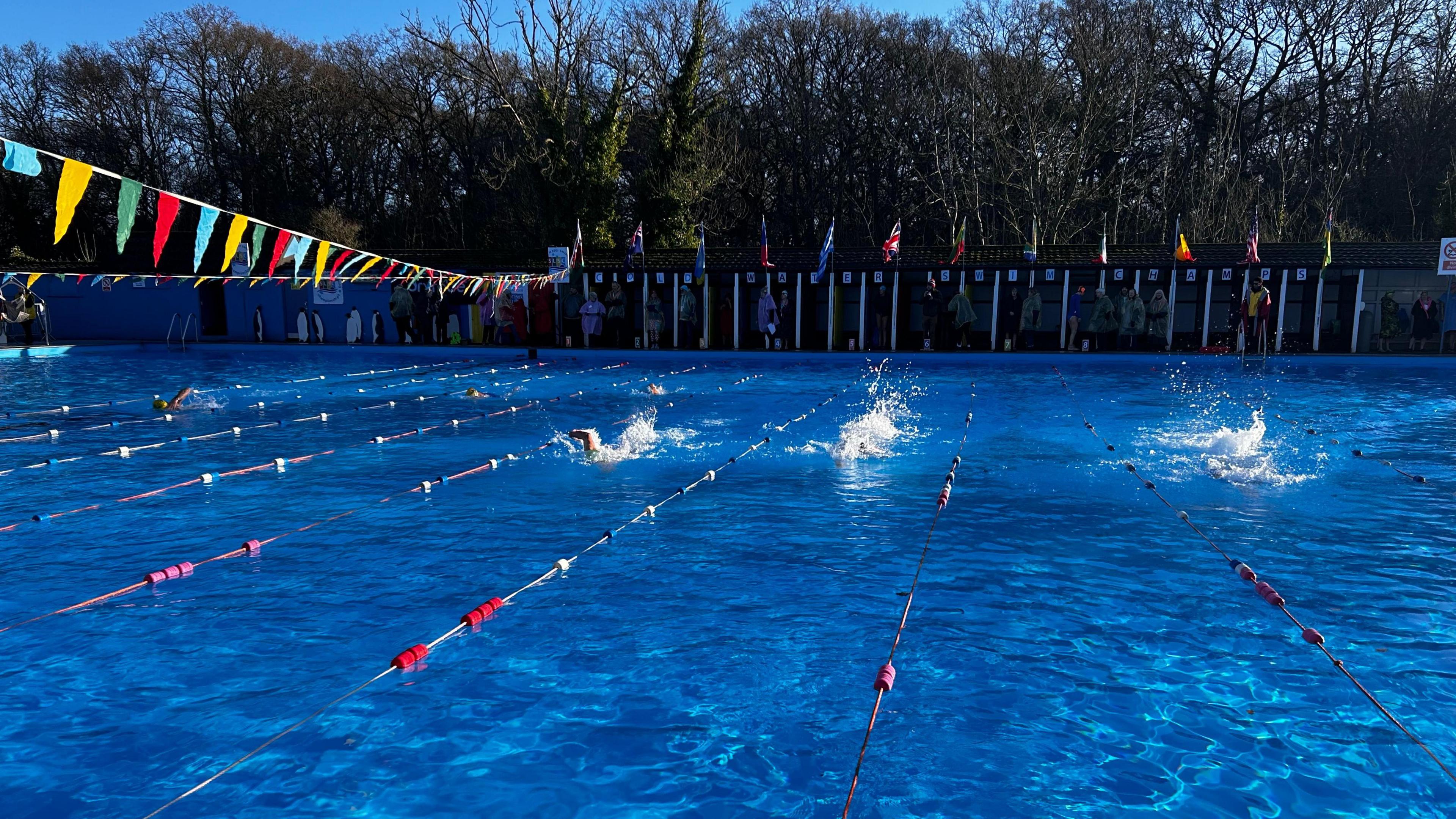 A view of swimmers making splashes as they swim across the pool.