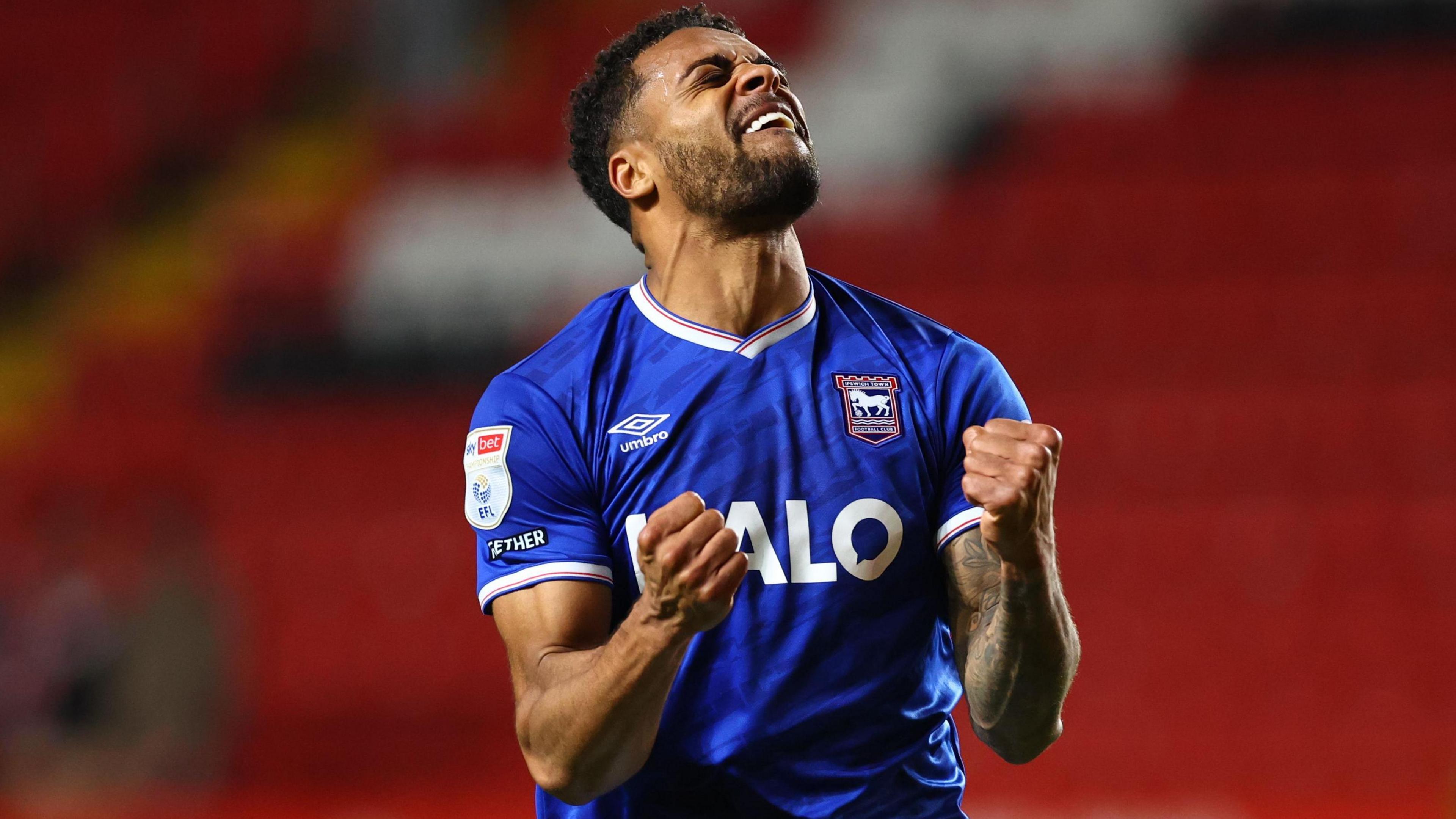 Darnell Furlong, wearing Ipswich's blue home shirt, celebrates at full-time after the win against Charlton with both fists clenched and his eyes closed