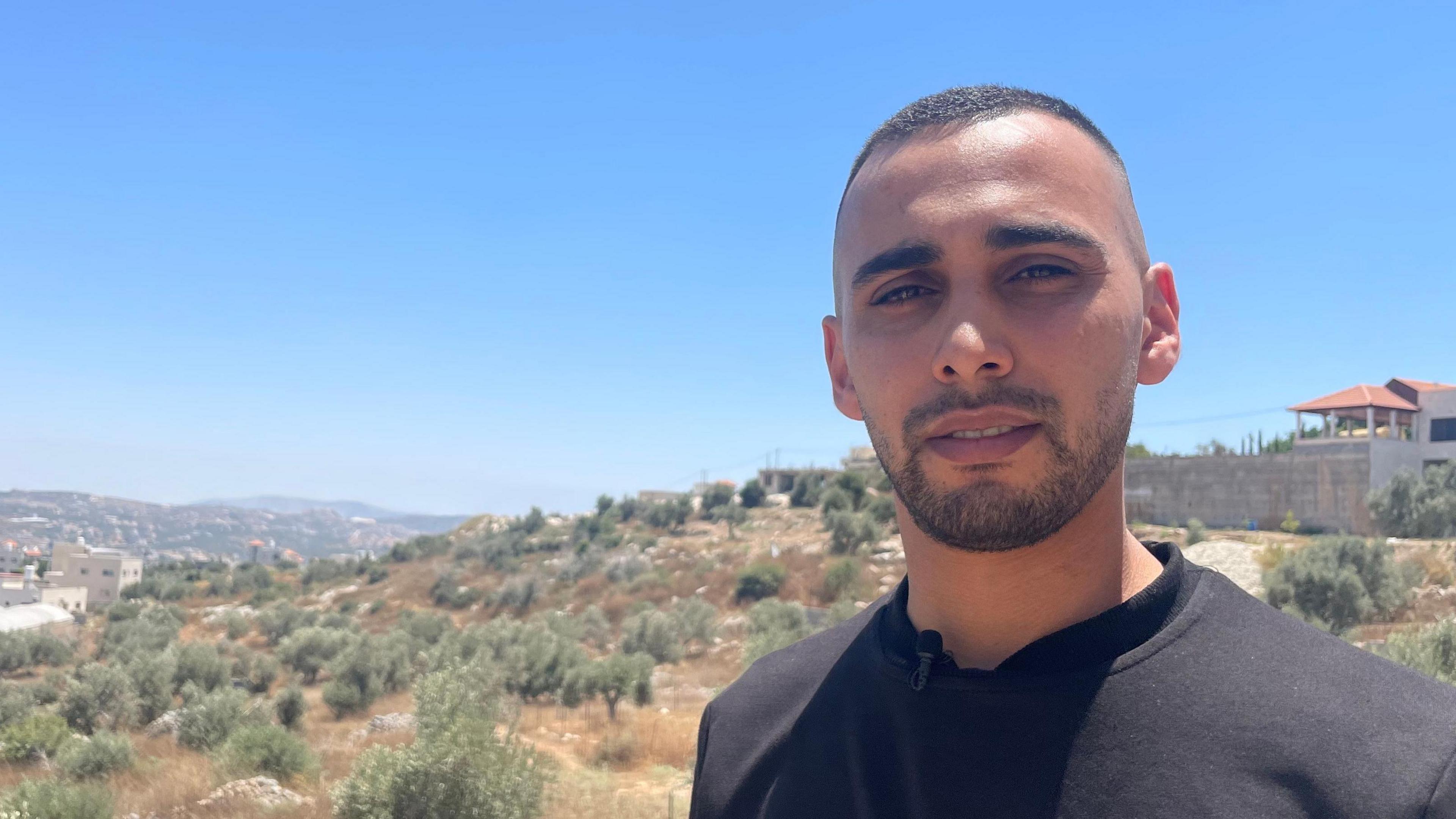 Palestinian man Hesham Isleit, pictured in a black t-shirt. He says he was tied to a jeep by the Israeli army.