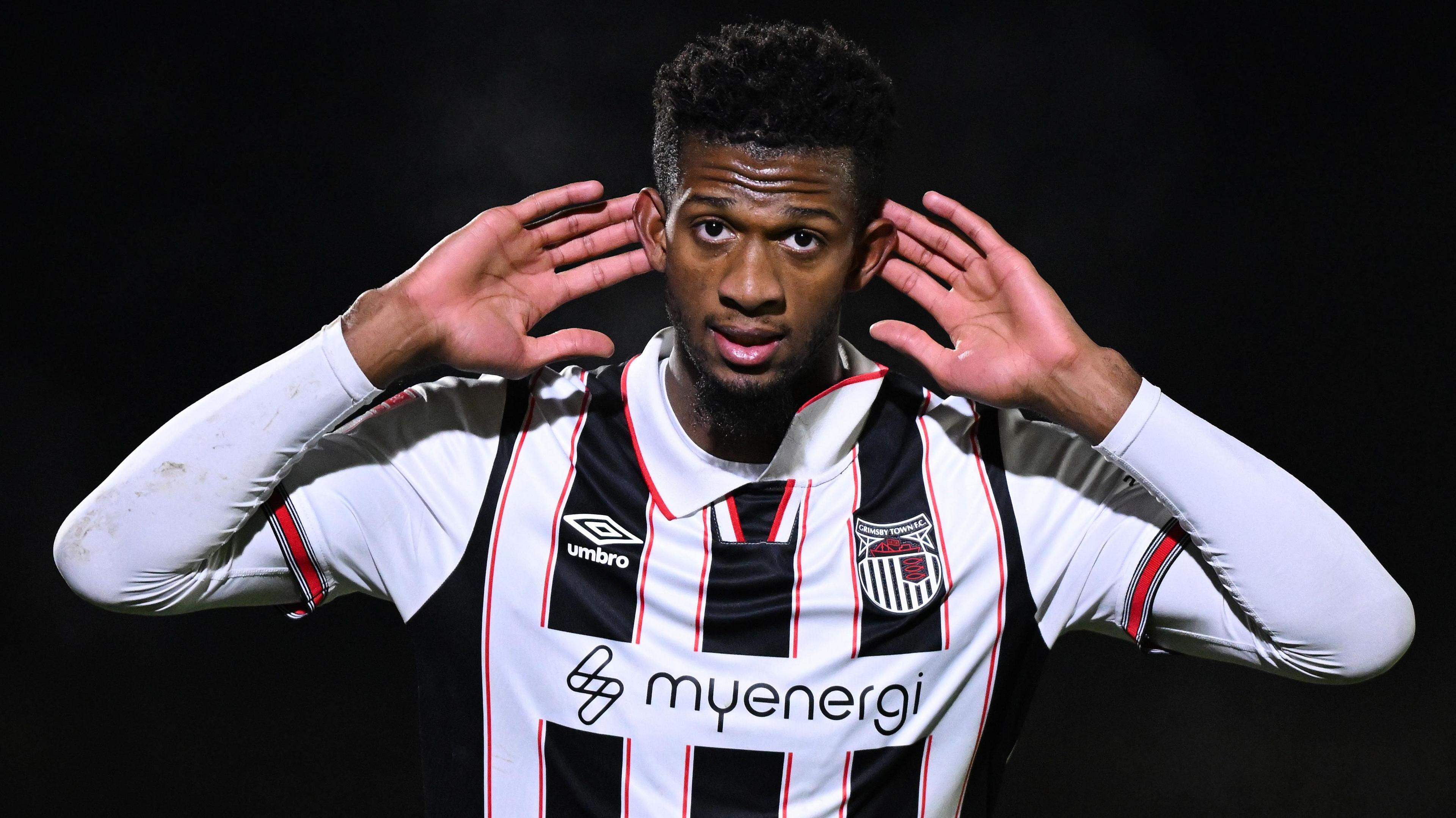 Justin Obikwu cups his ears in celebration after scoring for Grimsby Town