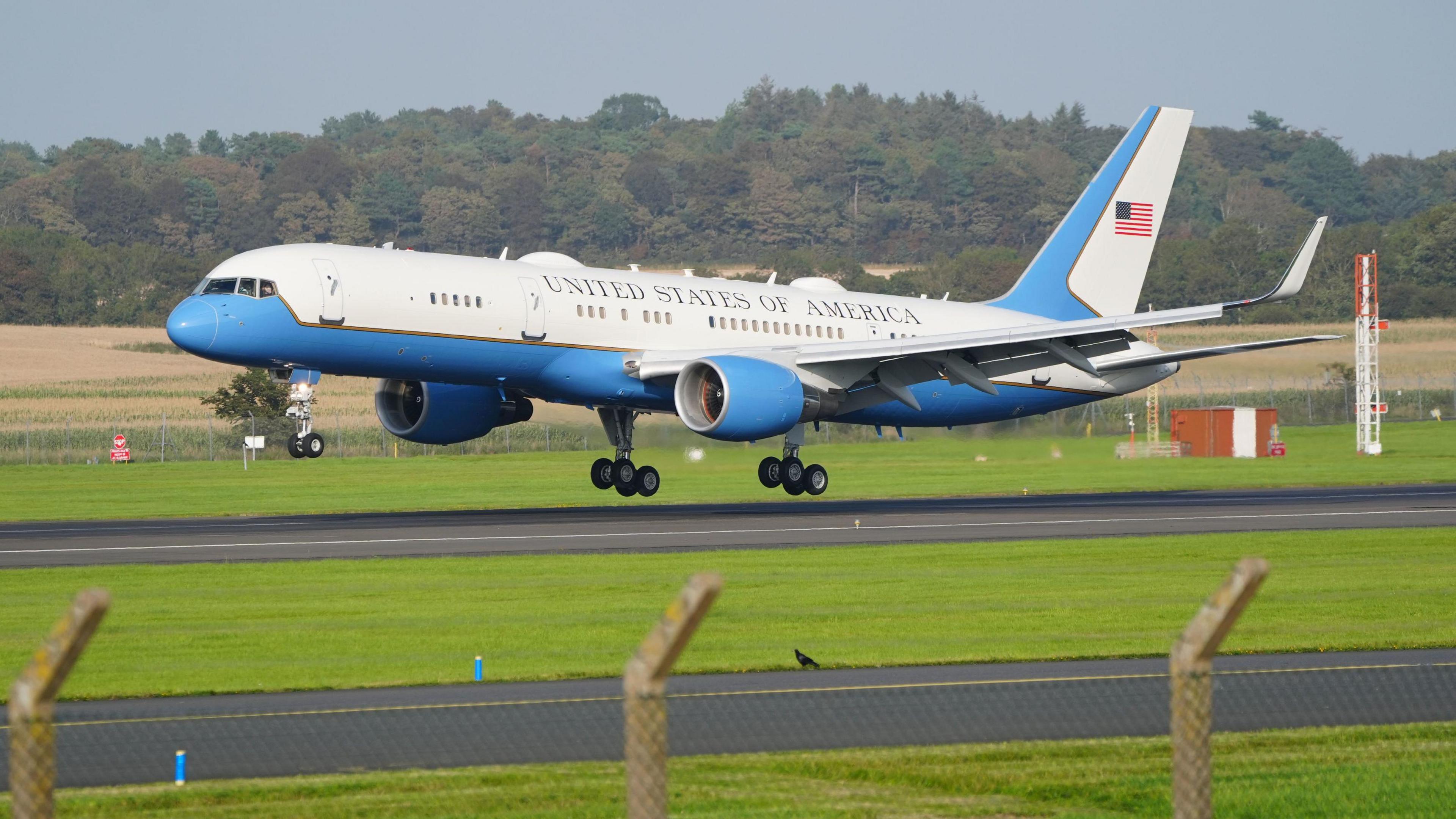 Air Force Two, a blue and white airplane landing on tarmac. It says United States of America and has the American flag painted on the tail 